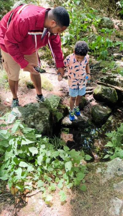 Mack Scott III with his son, Mack Scott IV, on the Narragansett reservation drinking from a sacred spring. (Courtesy of Mack Scott III via The Public's Radio)