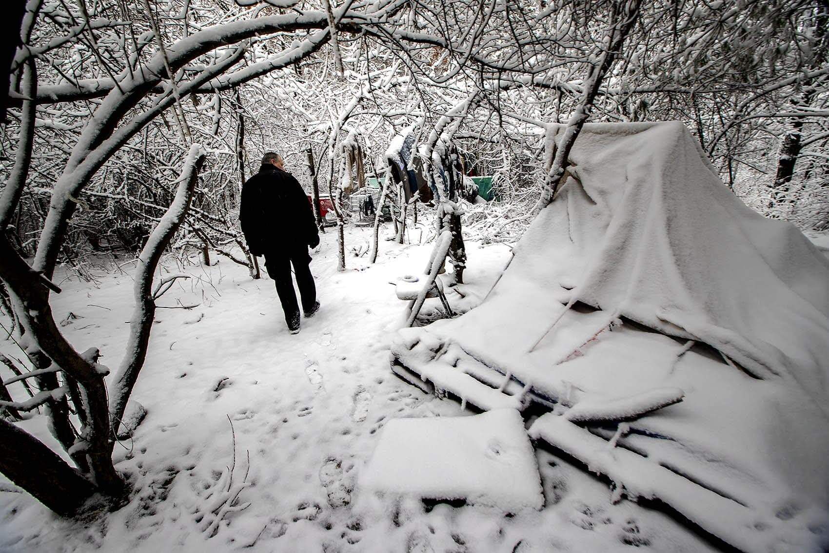 A Worcester police officer Walter Duffy walks into a homeless encampment in the woods in 2019. (Jesse Costa/WBUR)