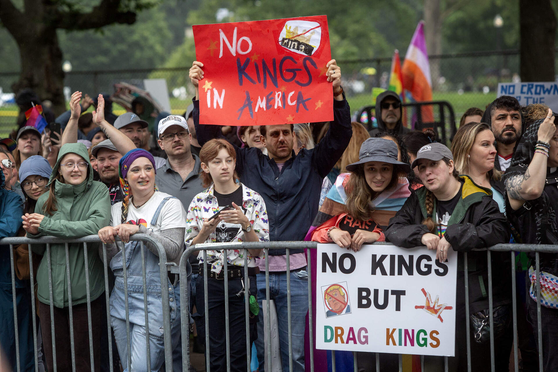 Demonstrators hold up "No Kings" signs on Charles Street during the Boston Pride Parade. (Robin Lubbock/WBUR)