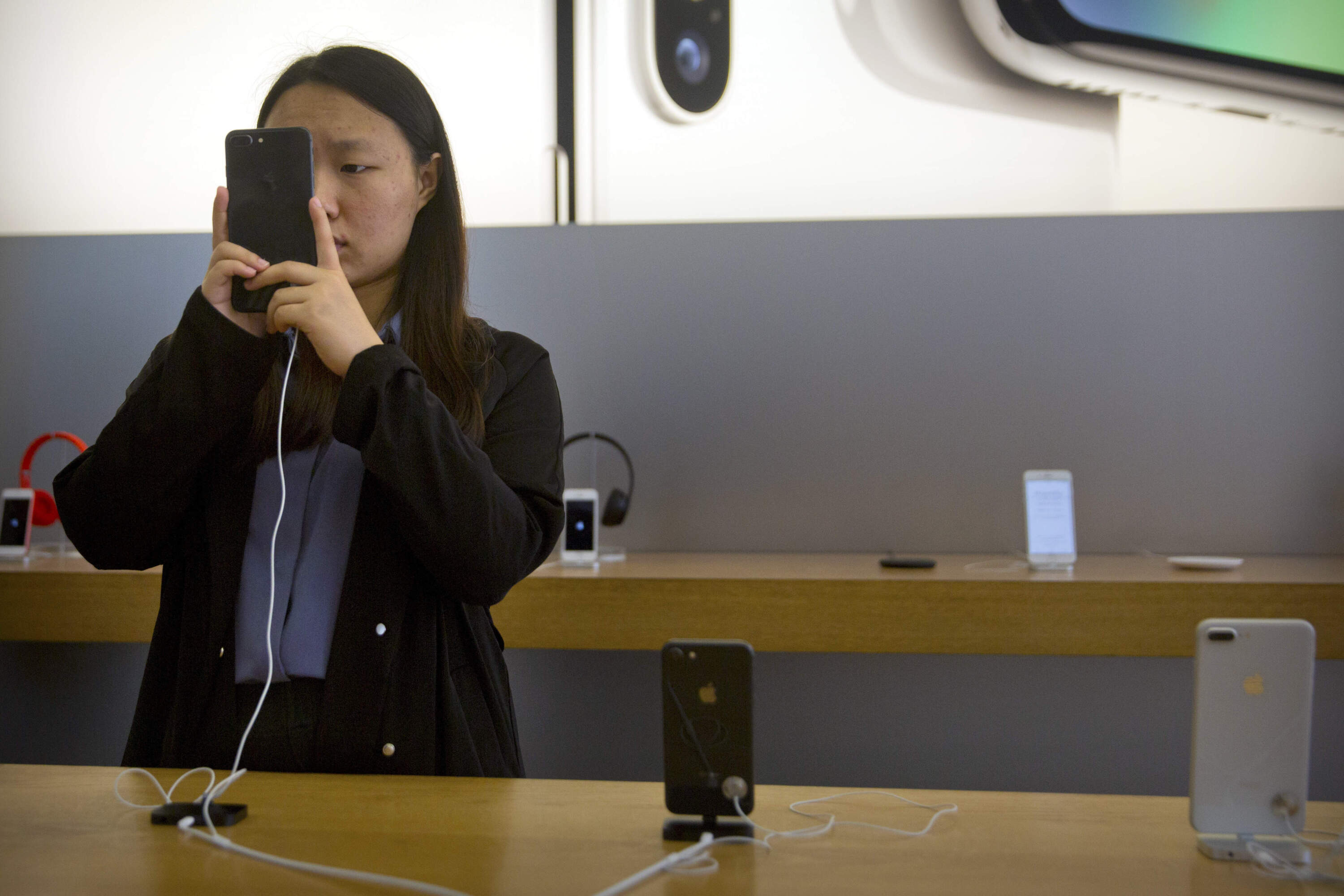 A woman tries out an iPhone at an Apple Store in Beijing, China, Friday, Oct. 20, 2017. (Mark Schiefelbein/AP)