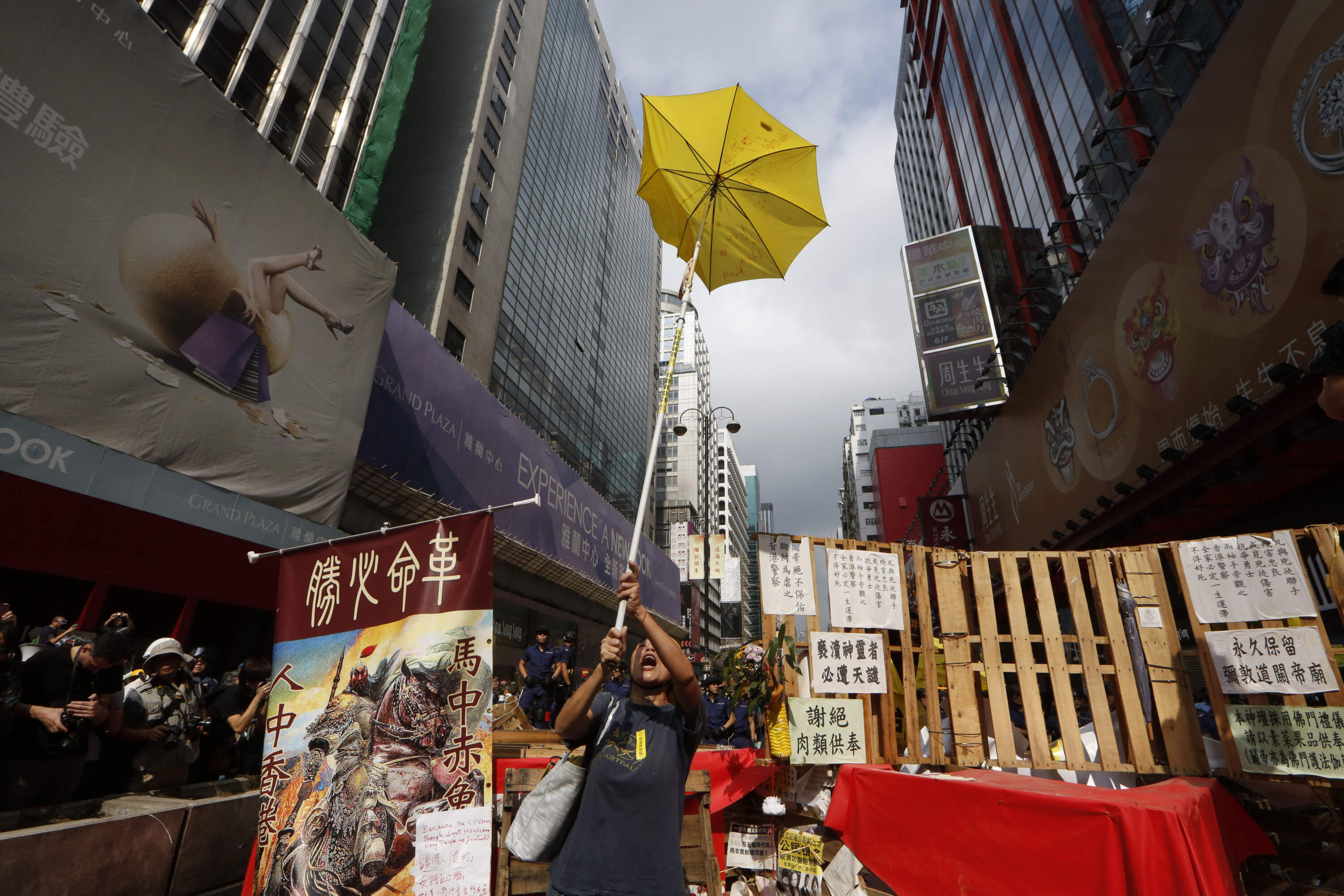 In this file photo taken Wednesday, Nov. 26, 2014, a protester holds a yellow umbrella, the symbol of Hong Kong's pro-democracy movement, at the barricades as the police keep clearing them away at an occupied area in Mong Kok district of Hong Kong. A legislative bill that harkened back on Beijing's promise to allow Hong Kong residents to vote for their leader, triggered massive demonstrations in Hong Kong's most crowded districts, led by young activists and lasting 79 days. The movement's organizers called it "Occupy Central with Love and Peace," but around the world, the sustained sit-in came to be known as the "Umbrella Revolution" for the yellow umbrellas which protesters used as shields against police pepper spray. (AP Photo/Kin Cheung)