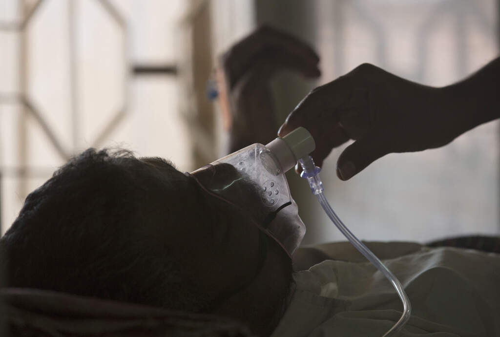 A relative adjusts the oxygen mask of a tuberculosis (TB) patient at a TB hospital on World Tuberculosis Day in Hyderabad, India, on March 24, 2018. (Mahesh Kumar/AP)