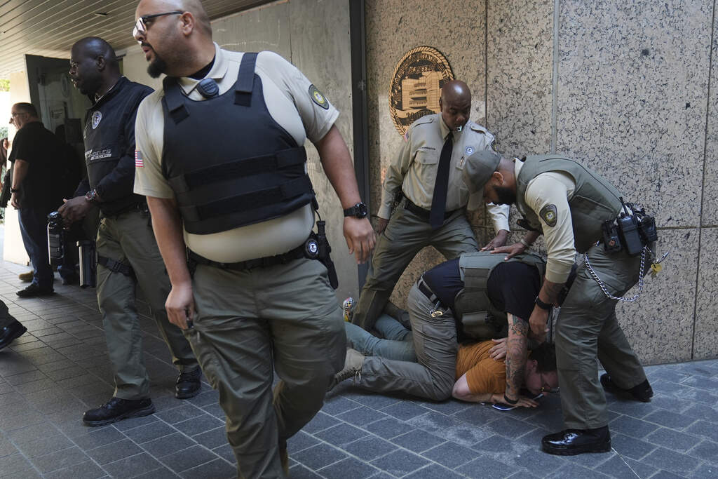 Law enforcement detain a protester at the U.S. Department of Justice Federal Bureau of Prisons after federal immigration authorities conducted an operation on Friday, June 6, 2025, in Los Angeles. (AP Photo/Jae C. Hong)
