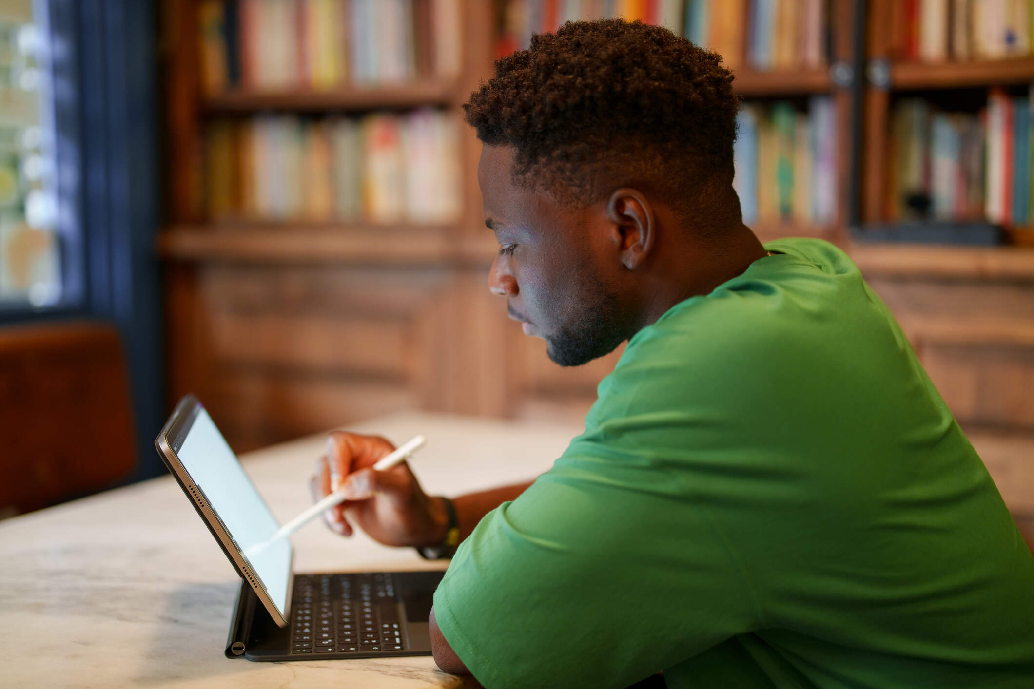 A young man works on a digital tablet in a library. (Getty Images)
