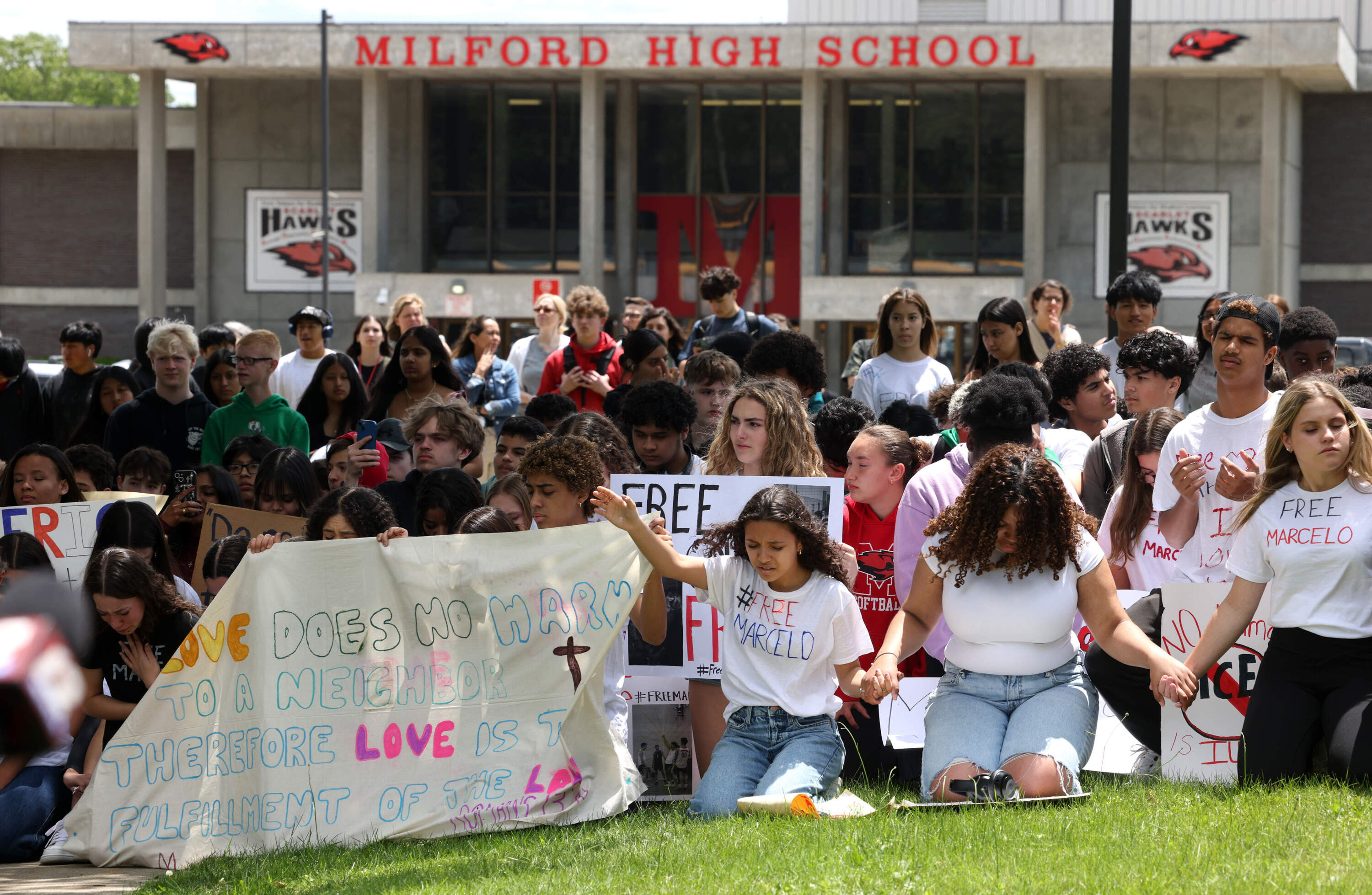 Students pray outside of Milford High School after walking out of school Monday to protest the detention of Marcelo Gomes Da Silva.