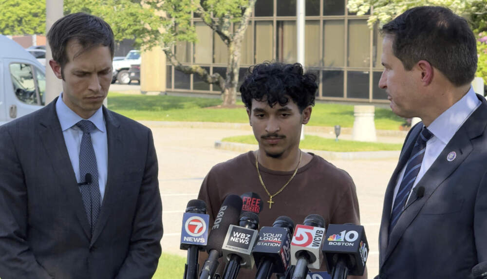 Marcelo Gomes da Silva speaks to journalists after being released from detention on June 5 as U.S. Reps. Seth Moulton, right, and Jake Auchincloss, listen. (Rodrique Ngowi/AP)