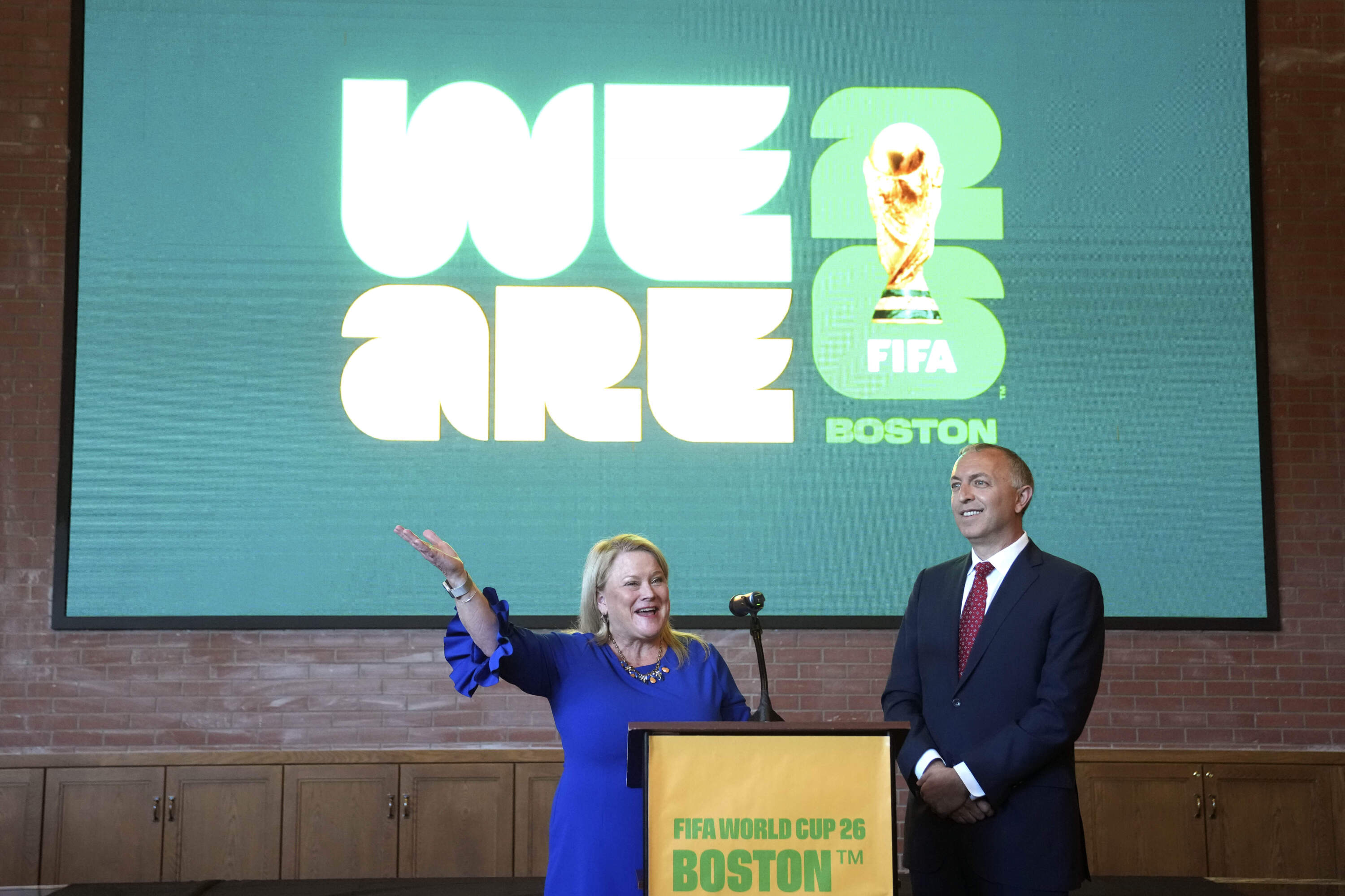 Martha J. Sheridan, the CEO of the local tourism bureau, Meet Boston, and Brian Bilello, president of Boston Soccer 2026, and the New England Revolution, right, stand in front of a projection of a logo for the local host committee's branding for the 2026 World Cup 2023. (Steven Senne/AP)