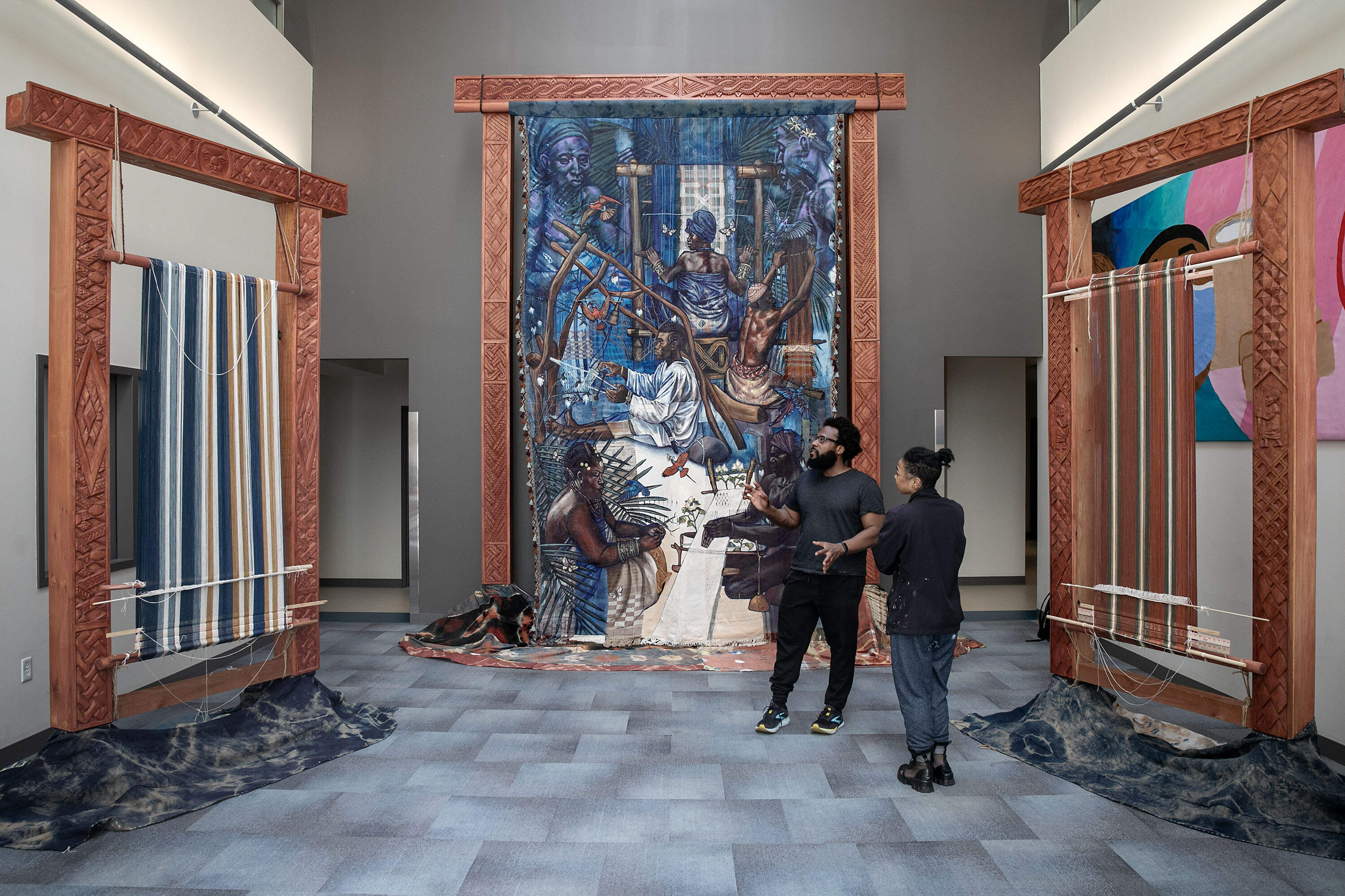 Artist Stephen Hamilton talks with woodcarver Naijah Garrett at the "Under the Spider's Web" installation at Roxbury Community College, in Boston. (Robin Lubbock/WBUR)