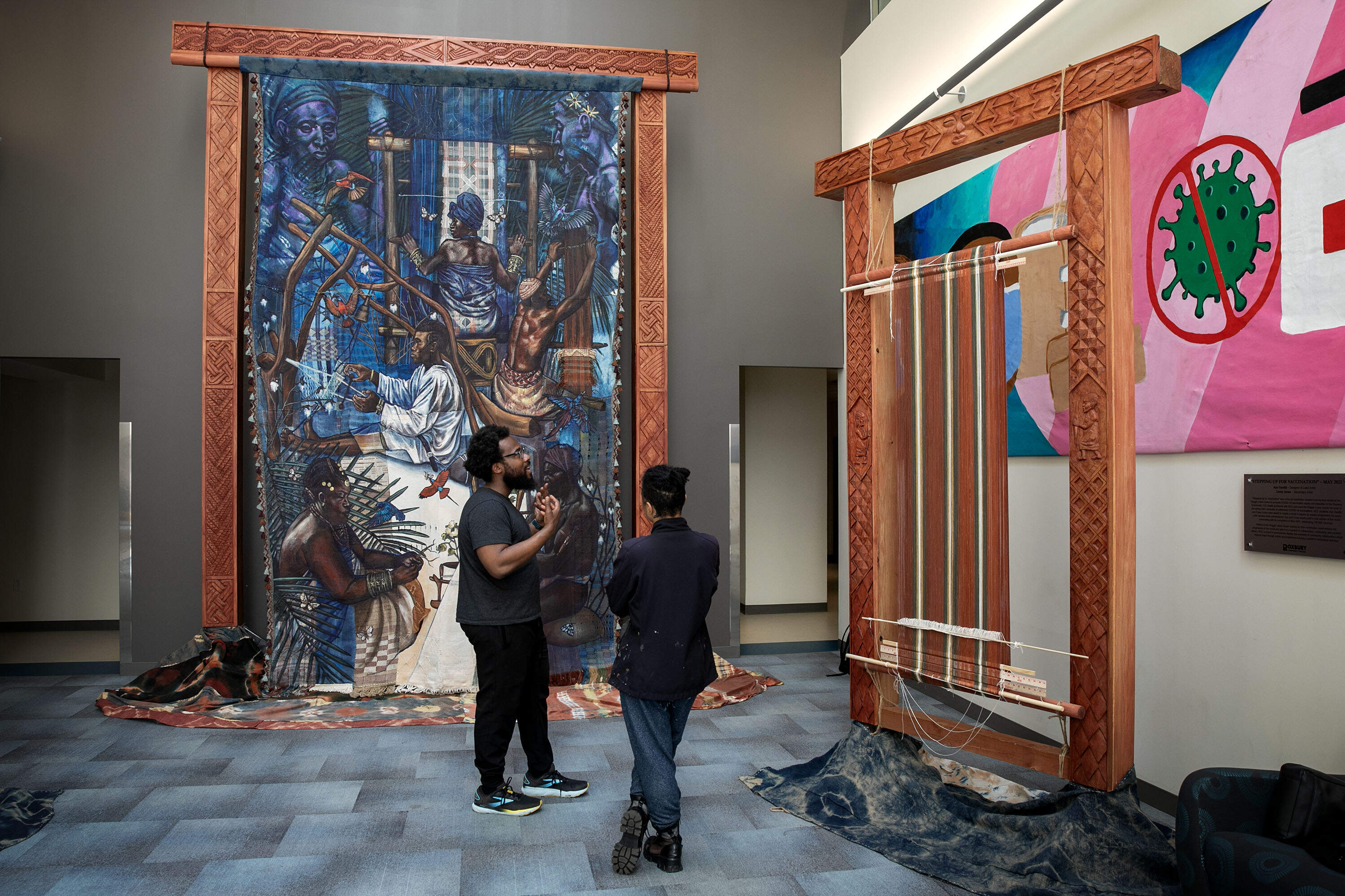 Artist Stephen Hamilton talks with woodcarver Naijah Garrett at the "Under the Spider's Web" installation at Roxbury Community College, in Boston. (Robin Lubbock/WBUR)