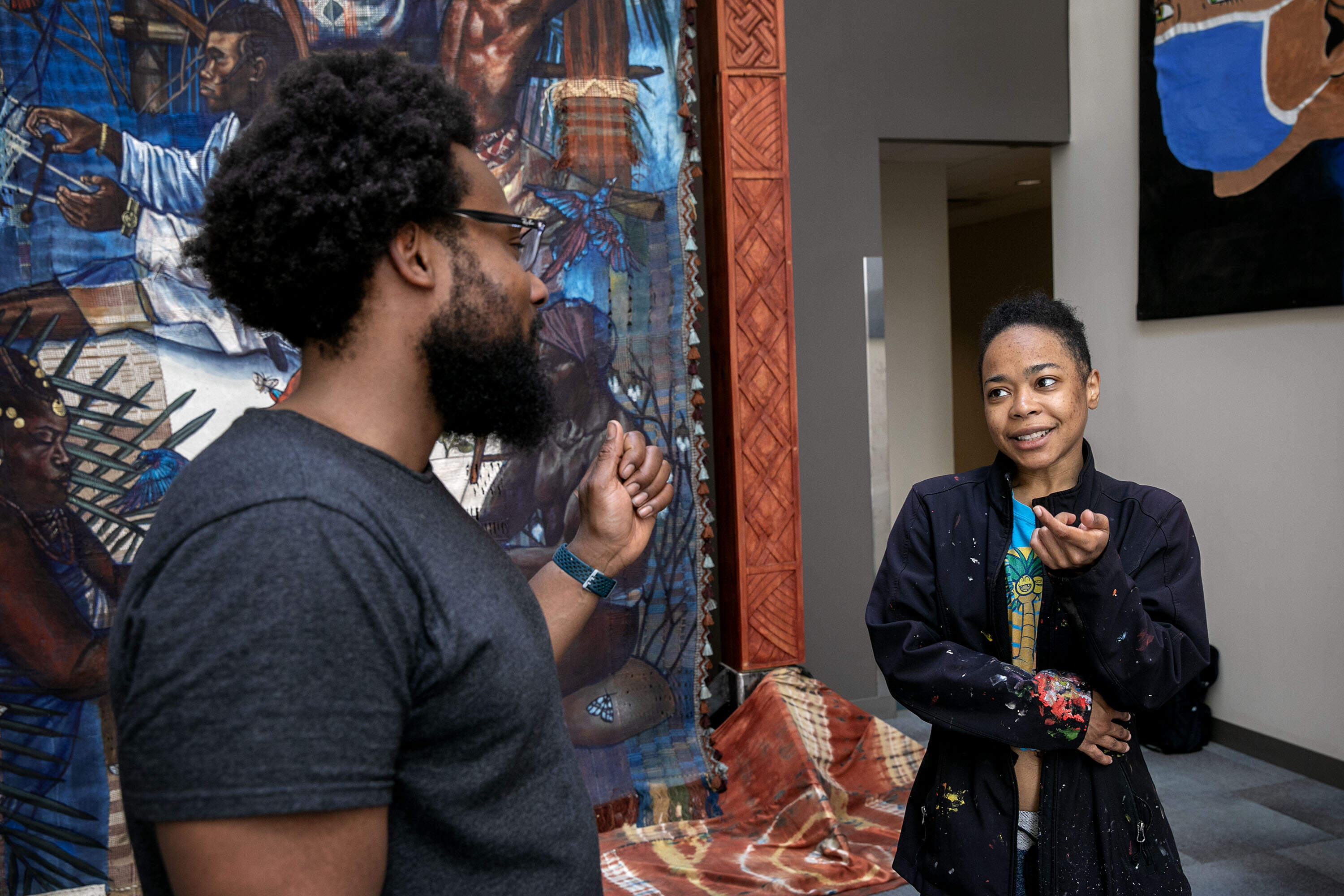Artist Stephen Hamilton talks with woodcarver Naijah Garrett at the "Under the Spider's Web" installation at Roxbury Community College, in Boston. (Robin Lubbock/WBUR)