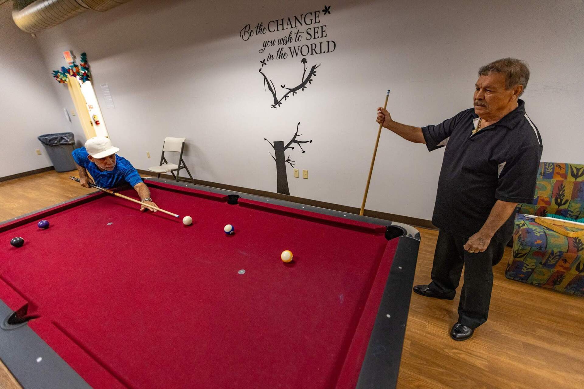 Jose Cruz watches as Jose Toledo take a shot during a game of pool at the Kenefick Park Elder Affairs Fitness Center. (Jesse Costa/WBUR)