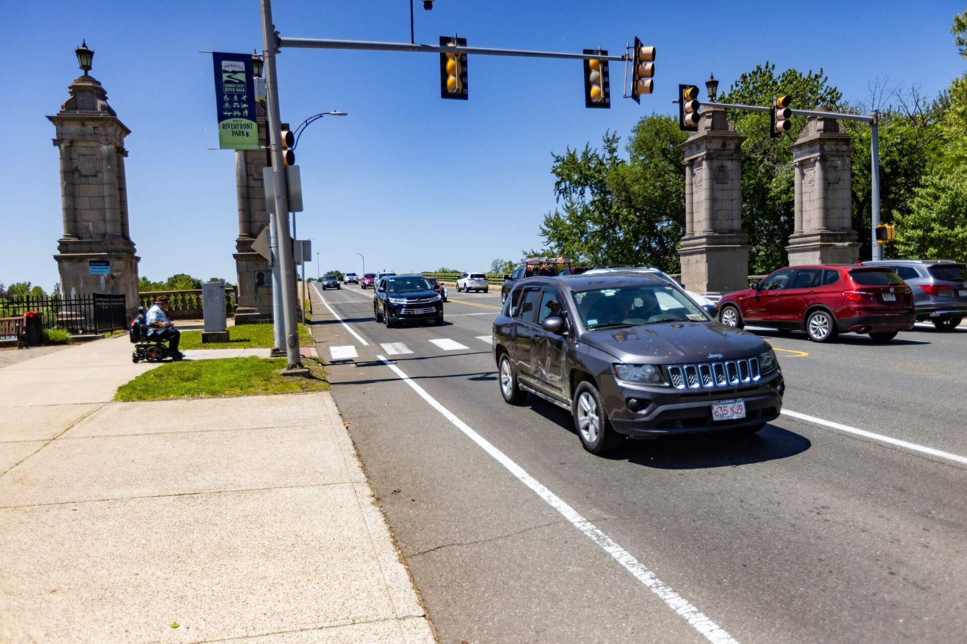A man in a wheelchair waits to cross a busy West Street at the North End Bridge in Springfield. City officials hoped to improve safety by renovating the intersection with more signals and expanded crosswalks with the canceled $20 million EPA grant. (Jesse Costa/WBUR)