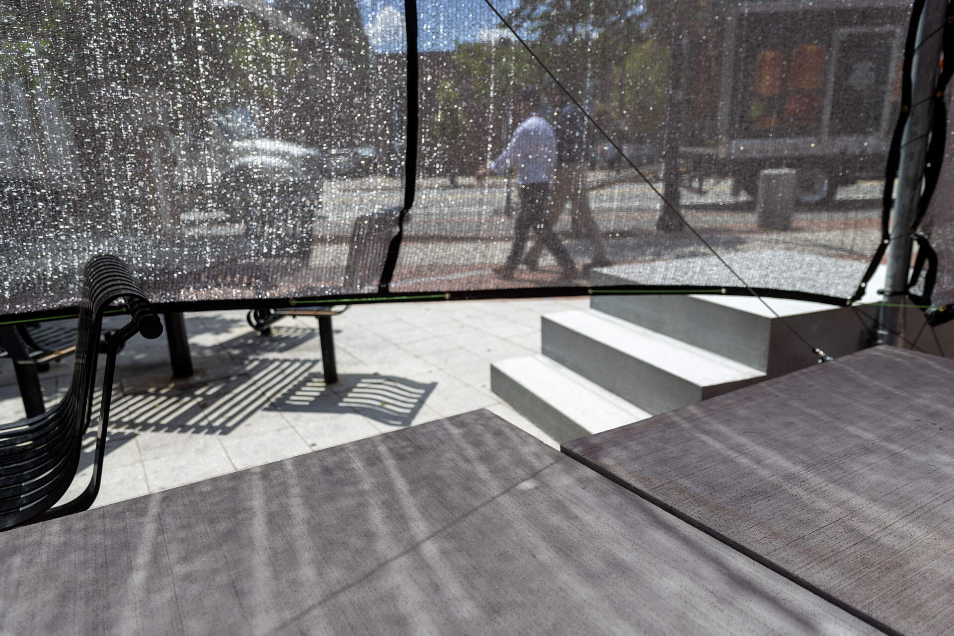 Beyond the shade of Gabriel Cira and Matthew Okazaki's “Sun Block,” pedestrians walk along Massachusetts Ave. in Cambridge. (Robin Lubbock/WBUR)