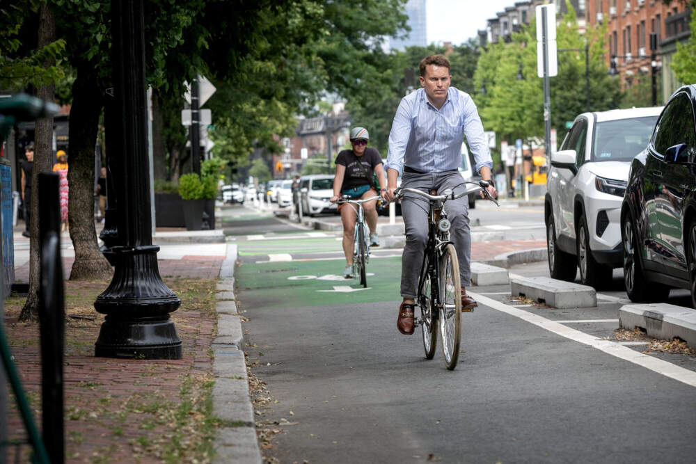 A cyclist rides along Tremont St. in Boston, where parked cars are separated from the bike lane by concrete blocks. (Robin Lubbock/WBUR)