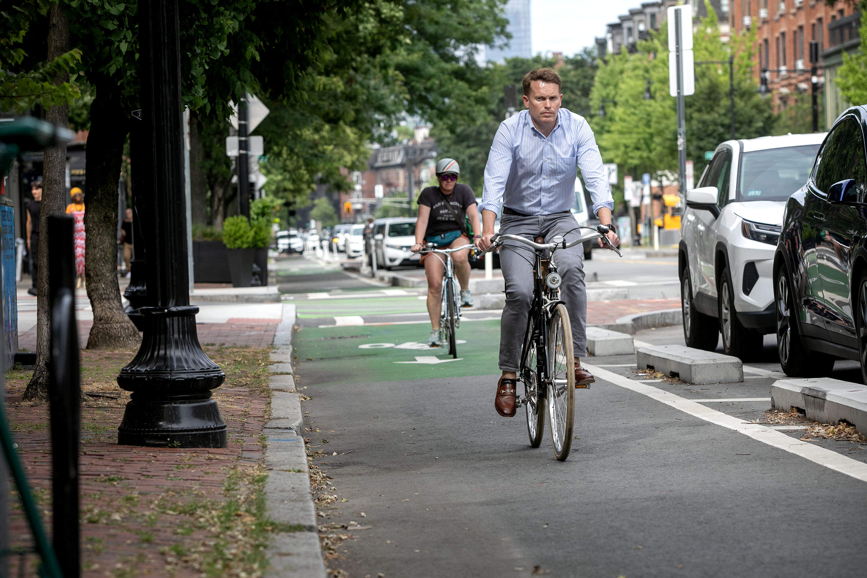 A cyclist rides along Tremont St. in Boston, where parked cars are separated from the bike lane by concrete blocks. (Robin Lubbock/WBUR)