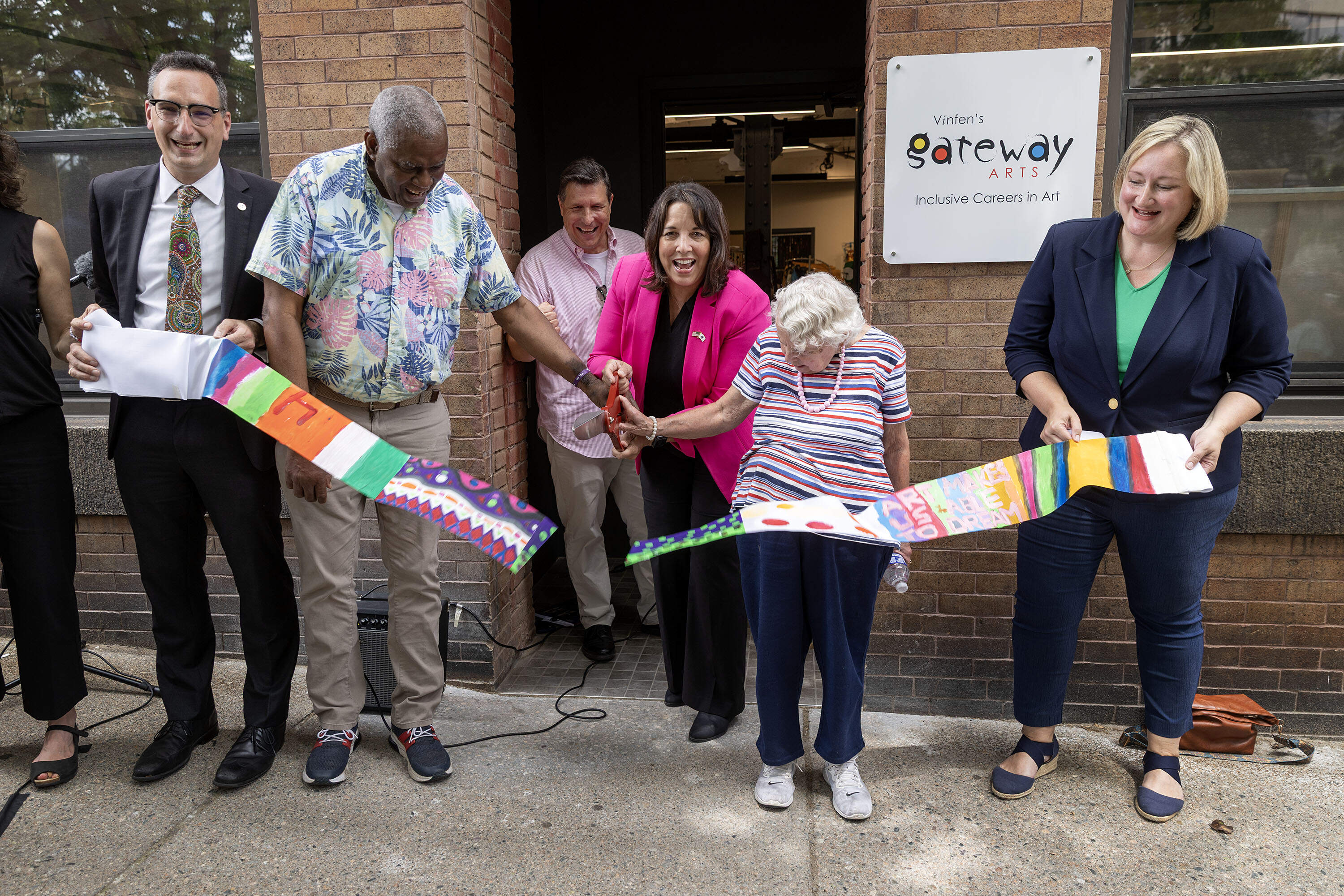 Artists Sydney Perry, Carmella Salvucci and Lt. Gov. Kim Driscoll cut a ribbon made by artists at Gateway Arts, for the opening of the center in Brookline, Mass. (Robin Lubbock/WBUR)