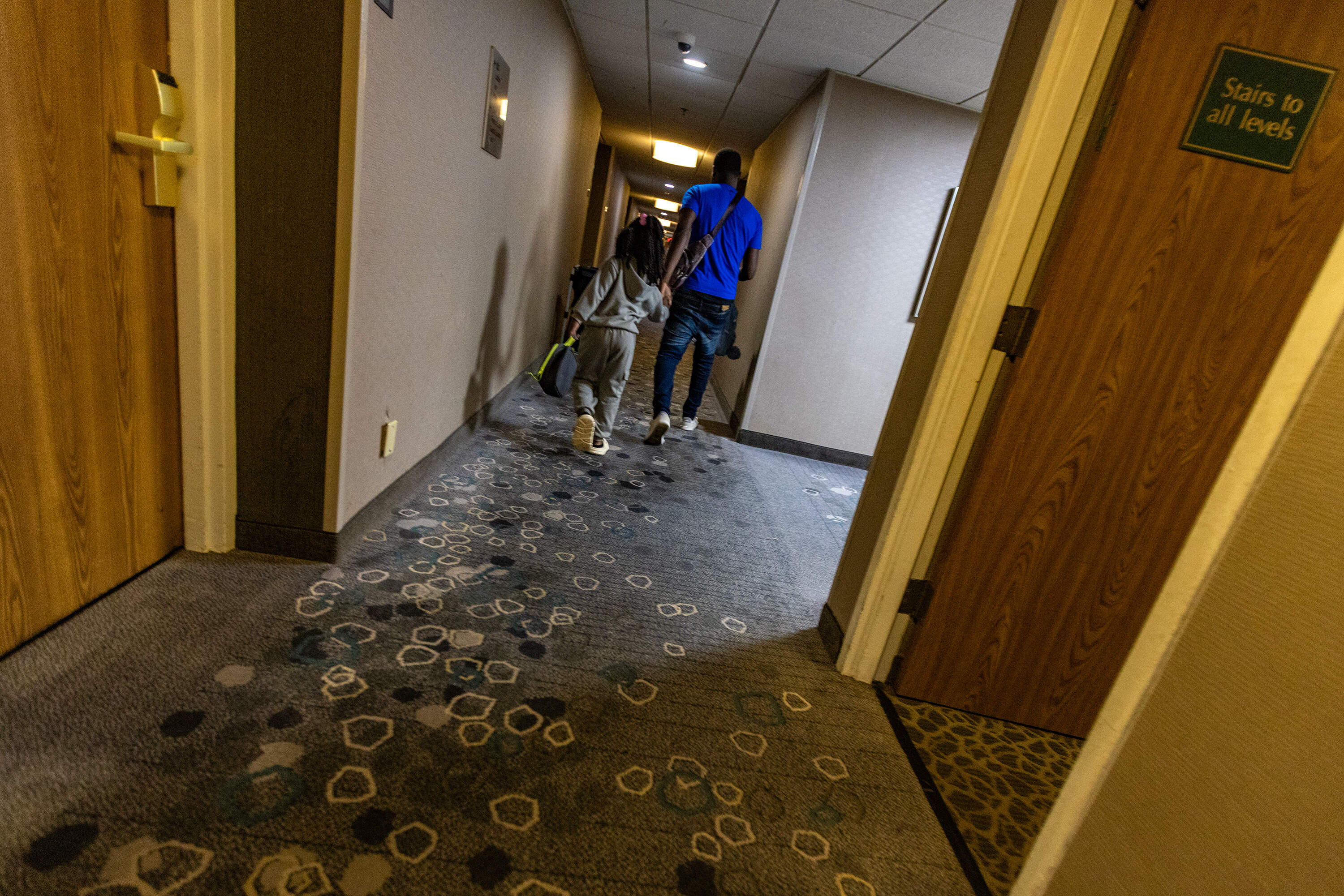 Two people walk down the hallway of a hotel in Stoughton converted into a shelter for migrants in 2024. (Jesse Costa/WBUR)
