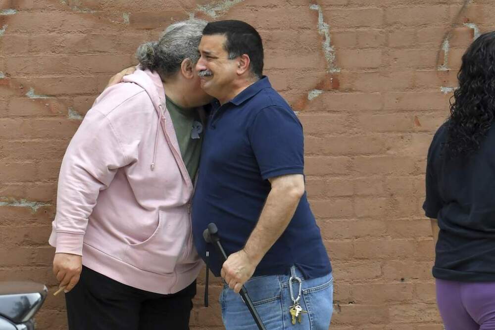 A unidentified man, right, embraces a resident of the Gabriel House assisted living facility, left, in Fall River outside a temporary shelter on Monday after a fire ravaged the facility. (Steven Senne/AP)