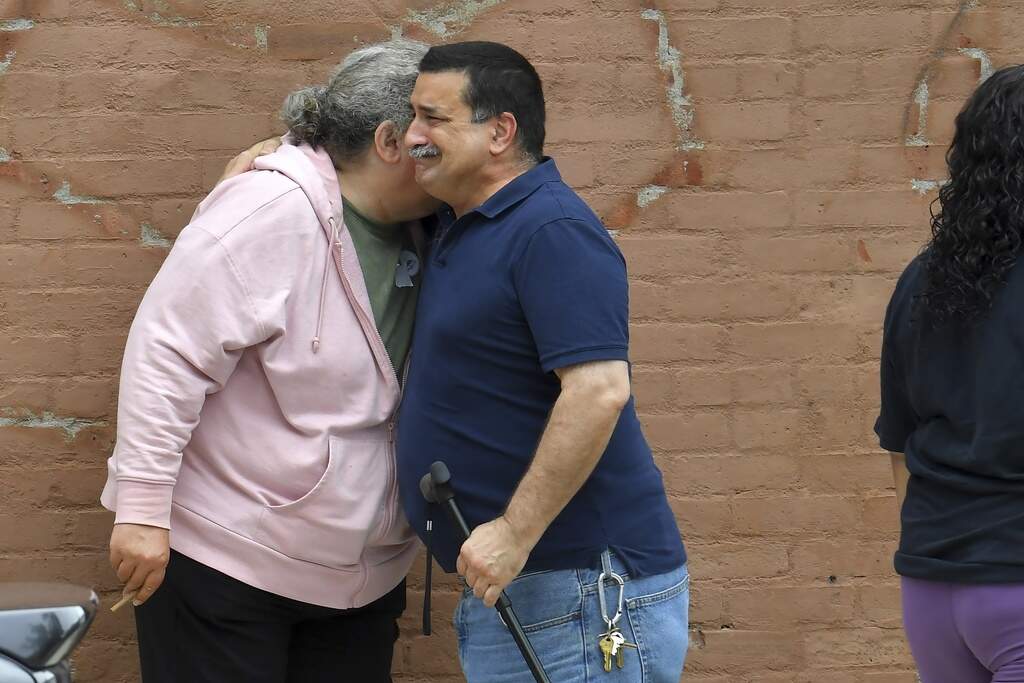 A unidentified man, right, embraces a resident of the Gabriel House assisted living facility, left, in Fall River outside a temporary shelter on Monday after a fire ravaged the facility. (Steven Senne/AP)
