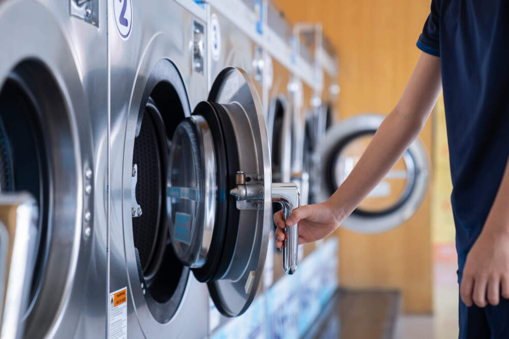 A young man loads a washing machine. (Getty Images)