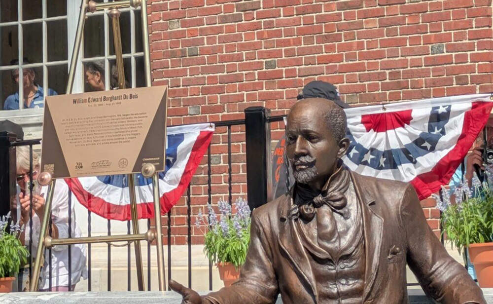 The new bronze sculpture of W.E.B. Du Bois sits on a marble bench outside the library in Great Barrington. (Jill Kaufman/NEPM)