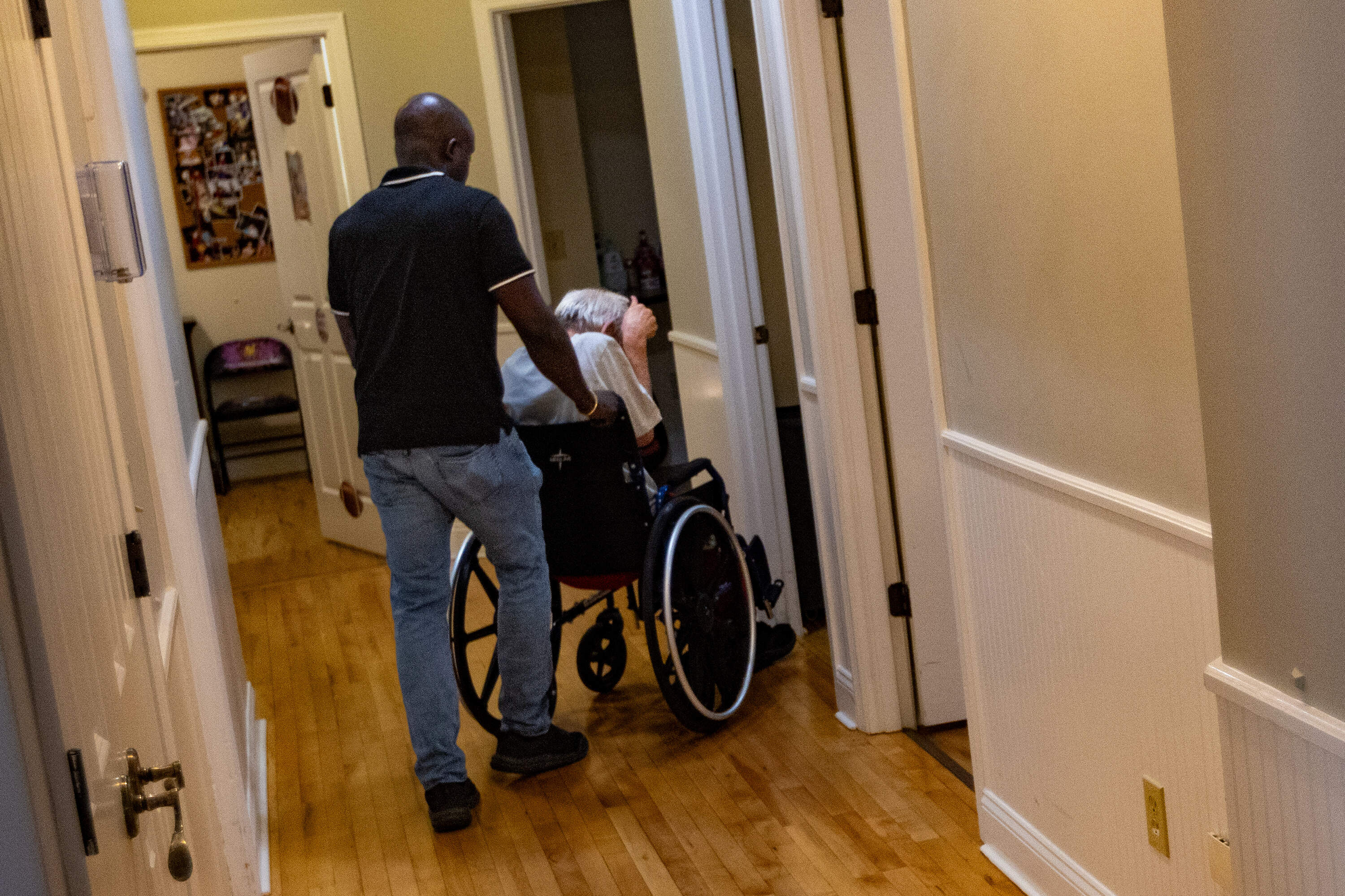 A Haitian worker wheels a resident to his room at the Road to Responsibility group home in Marshfield. (Jesse Costa/WBUR)