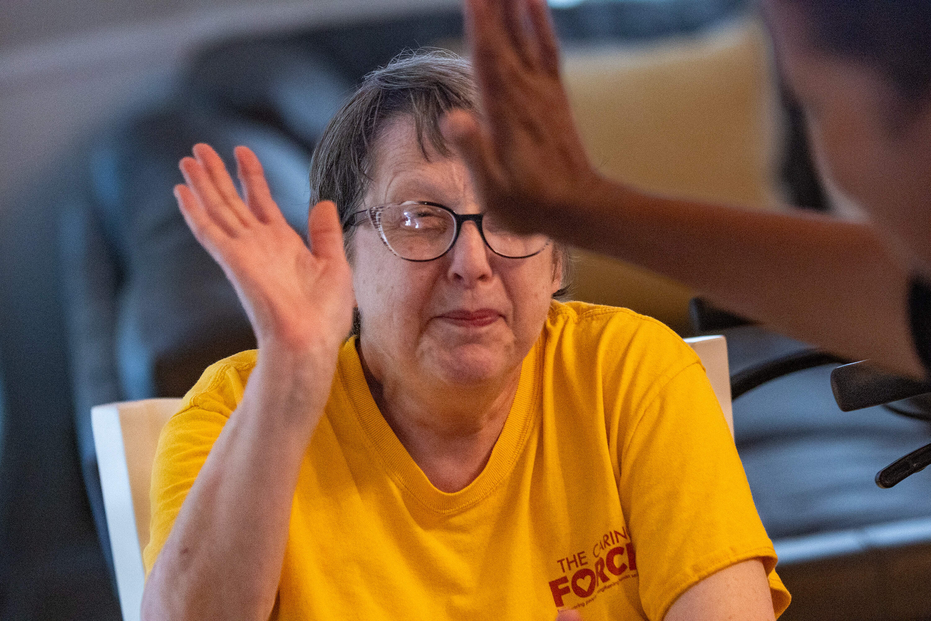 Resident Margie Hoffman gets a high five from a Haitian worker during dinner at the Road to Responsibility group home in Marshfield. (Jesse Costa/WBUR)