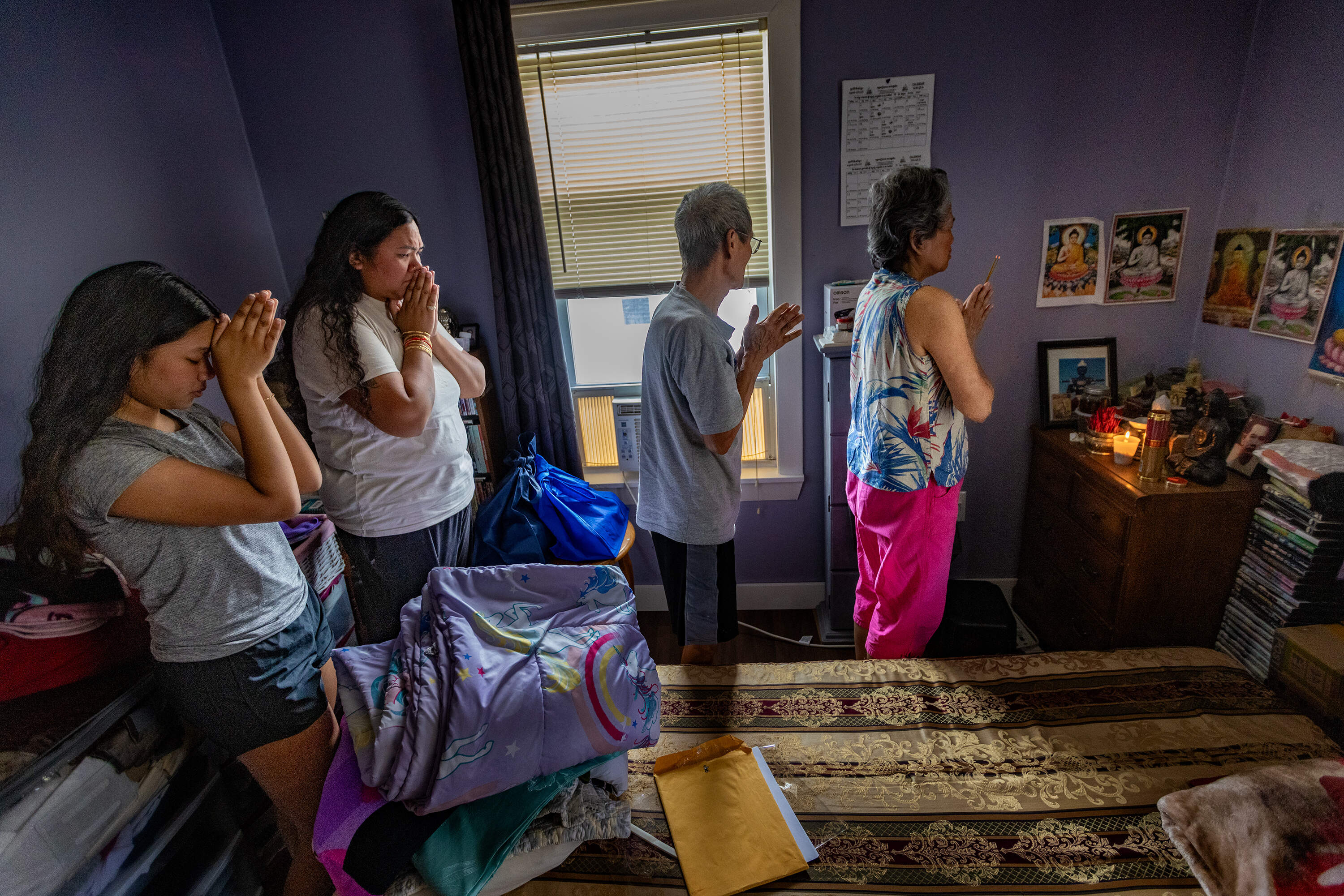 At their home in Lynn, Thearavy Chan, right, leads a prayer with her family for her son Samath Thoeun, while he is being detained by Immigrations and Customs Enforcement. (Jesse Costa/WBUR)