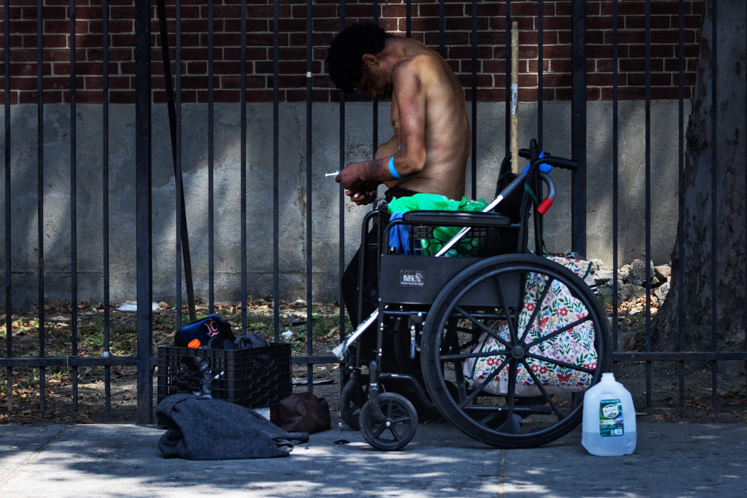 A man standing up from a wheelchair prepares to inject himself with a needle and syringe on Southampton Street in the Mass. and Cass area. (Jesse Costa/WBUR)