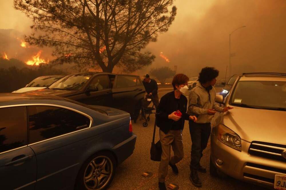 People flee from the advancing Palisades Fire by car and on foot in the Pacific Palisades neighborhood of Los Angeles on Tuesday, January. 7. (tienne Laurent/AP)