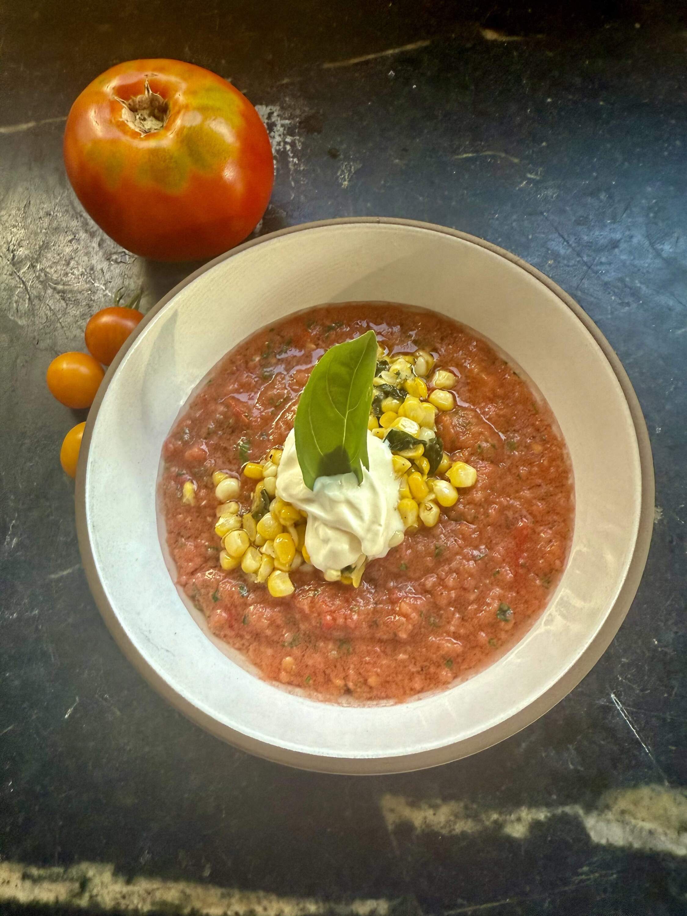 Cold tomato and cucumber soup with sauteed corn and basil topping. (Kathy Gunst/Here & Now)