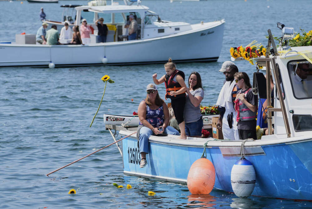 A child tosses a sunflower into the water in honor of Sunshine Stewart. (Robert F. Bukaty/AP)