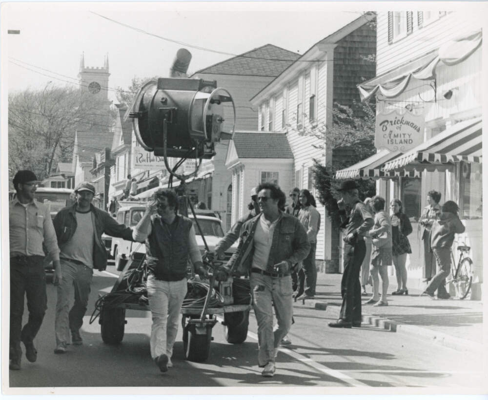 The "Jaws" lighting crew rolls equipment down Main Street in Edgartown. A "Brickman's of Amity Island" prop sign hangs in the background. (Courtesy of Edith Blake/Martha's Vineyard Museum)