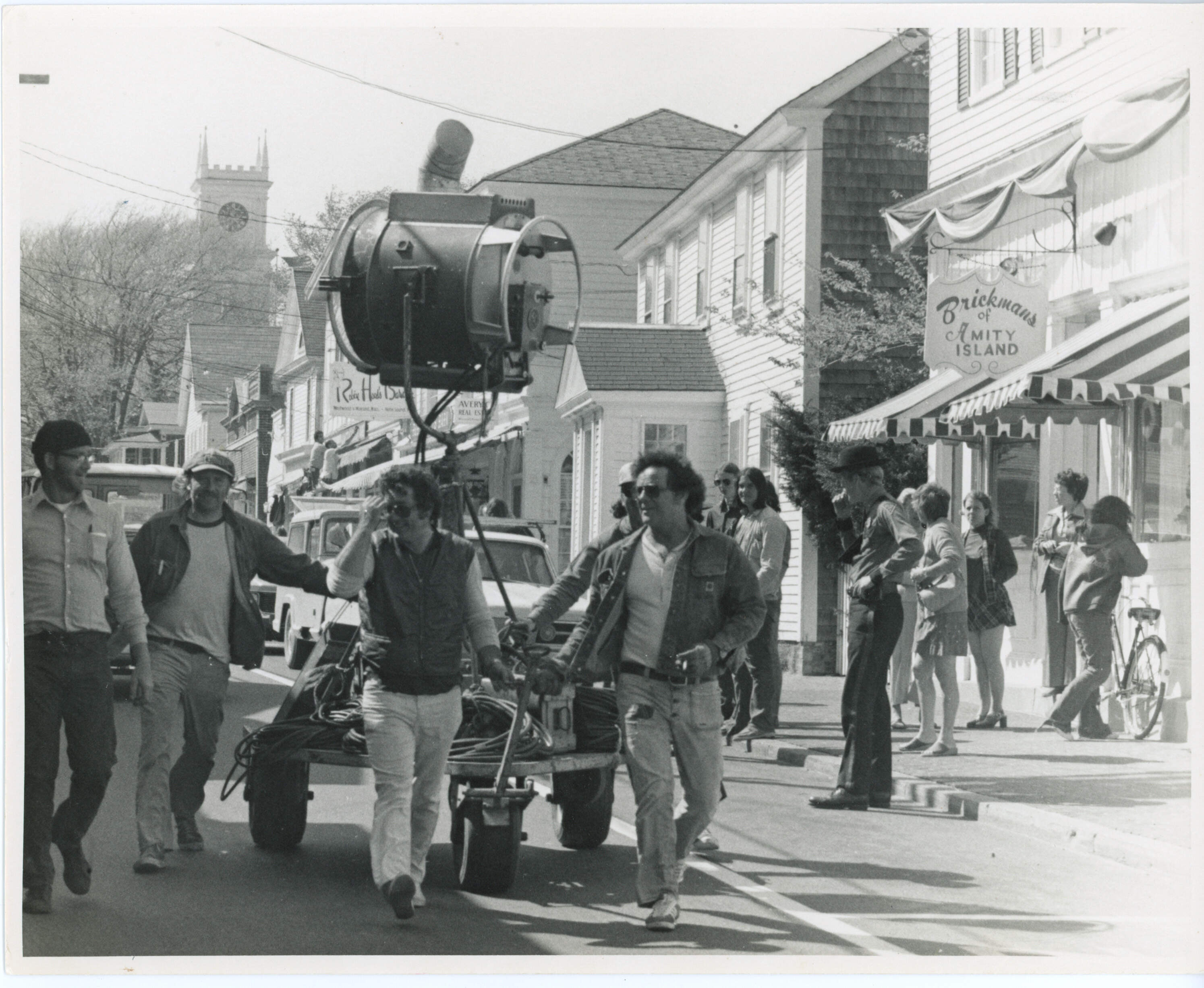 The "Jaws" lighting crew rolls equipment down Main Street in Edgartown. A "Brickman's of Amity Island" prop sign hangs in the background. (Courtesy of Edith Blake/Martha's Vineyard Museum)