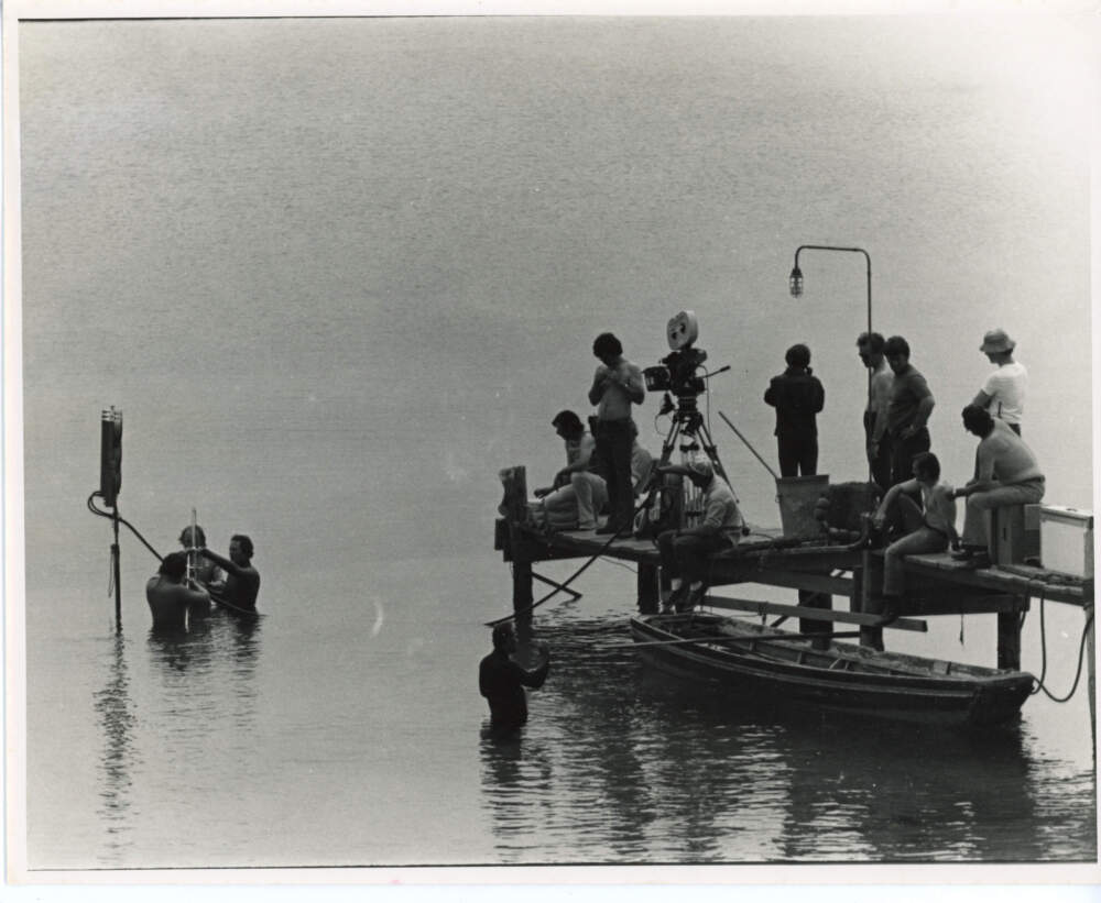 Crew members prepare for a shot in the ocean. Director Steven Spielberg stands shirtless on the dock to the left of the camera. (Courtesy of Edith Blake/Martha's Vineyard Museum)