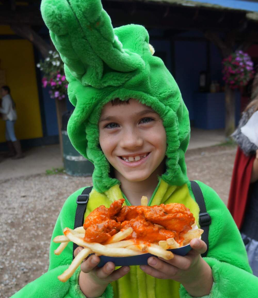 A child dressed as a dragon holds a plate of "dragon wings with fryes." (Courtesy of Julie Dennehy/King Richard's Faire)