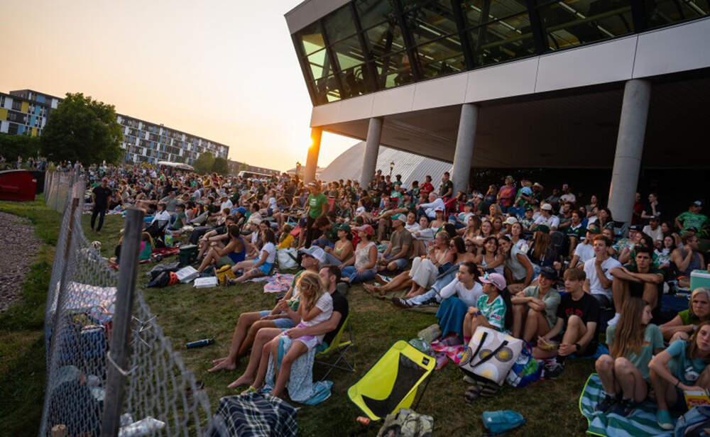 Fans sit on a hill outside the stadium to catch the League Two national championship. (Brian Stevenson/Vermont Public)