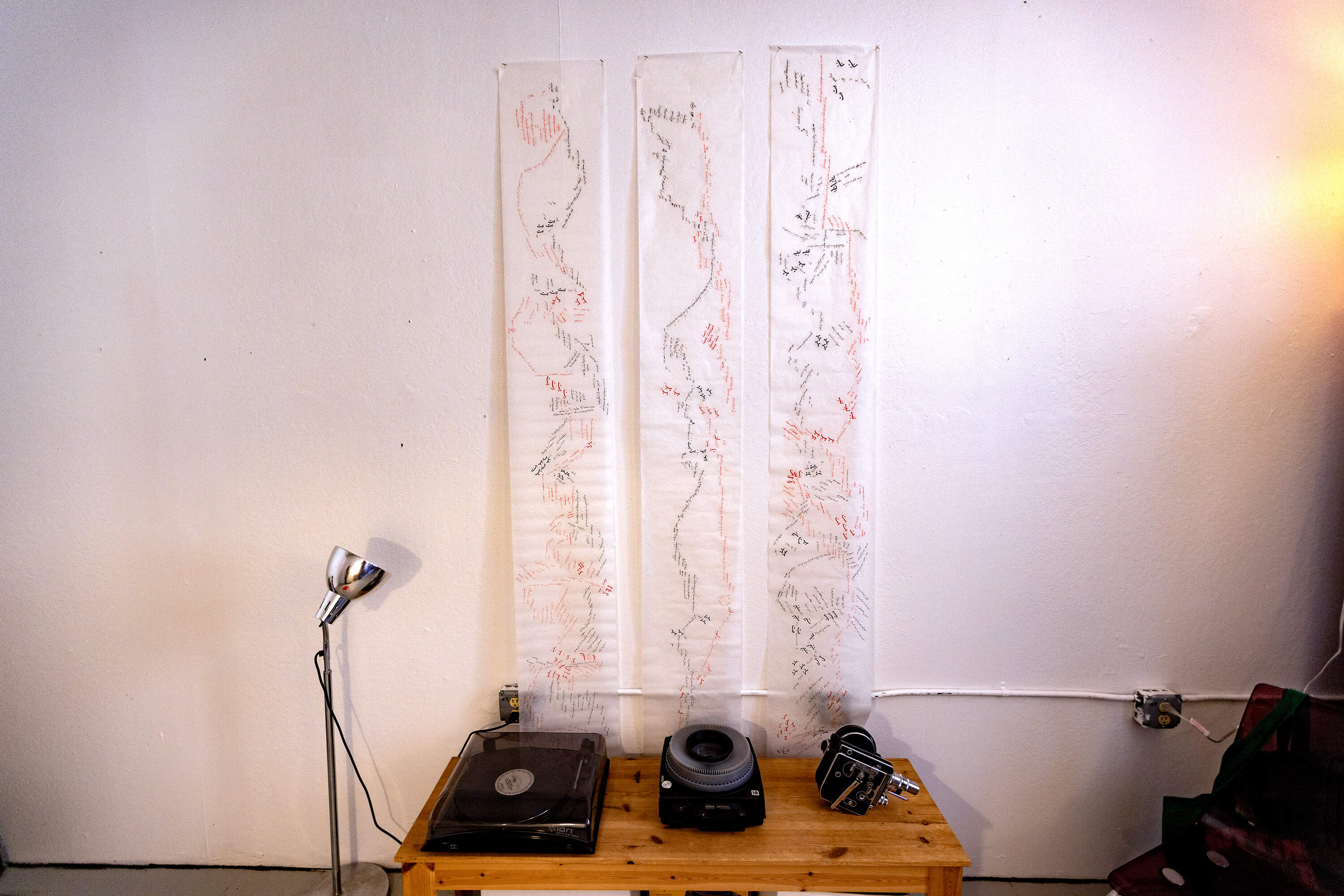 Sarabi's inscribed pieces of parchment drape down to the floor in her office at the Boston Center for the Arts. (Jesse Costa/WBUR)