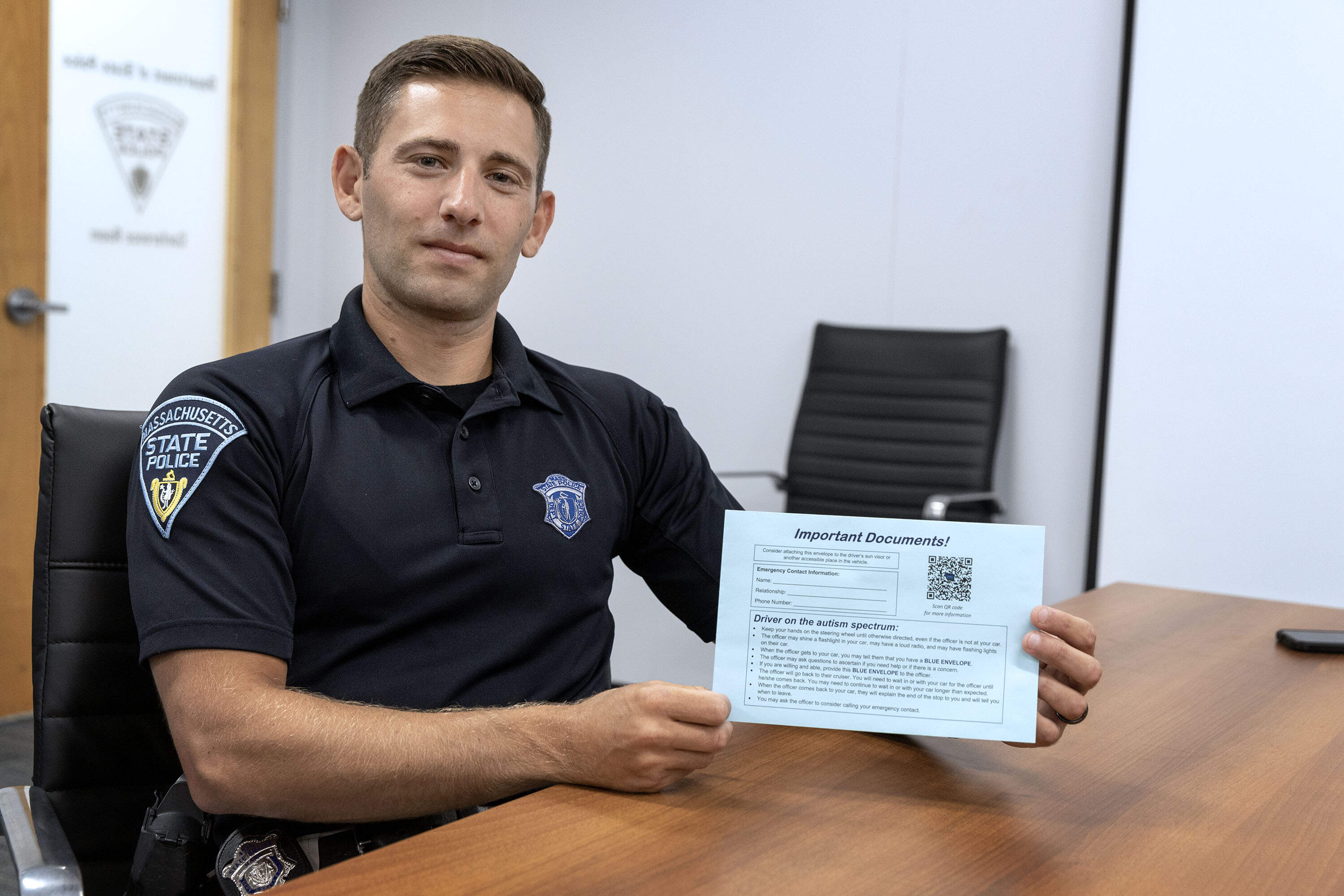 Mass. State Police Trooper Derek Henneberry holds a Blue Envelope with instructions that aim to assist officers during an incident involving a person with autism spectrum disorder. (Robin Lubbock/WBUR)