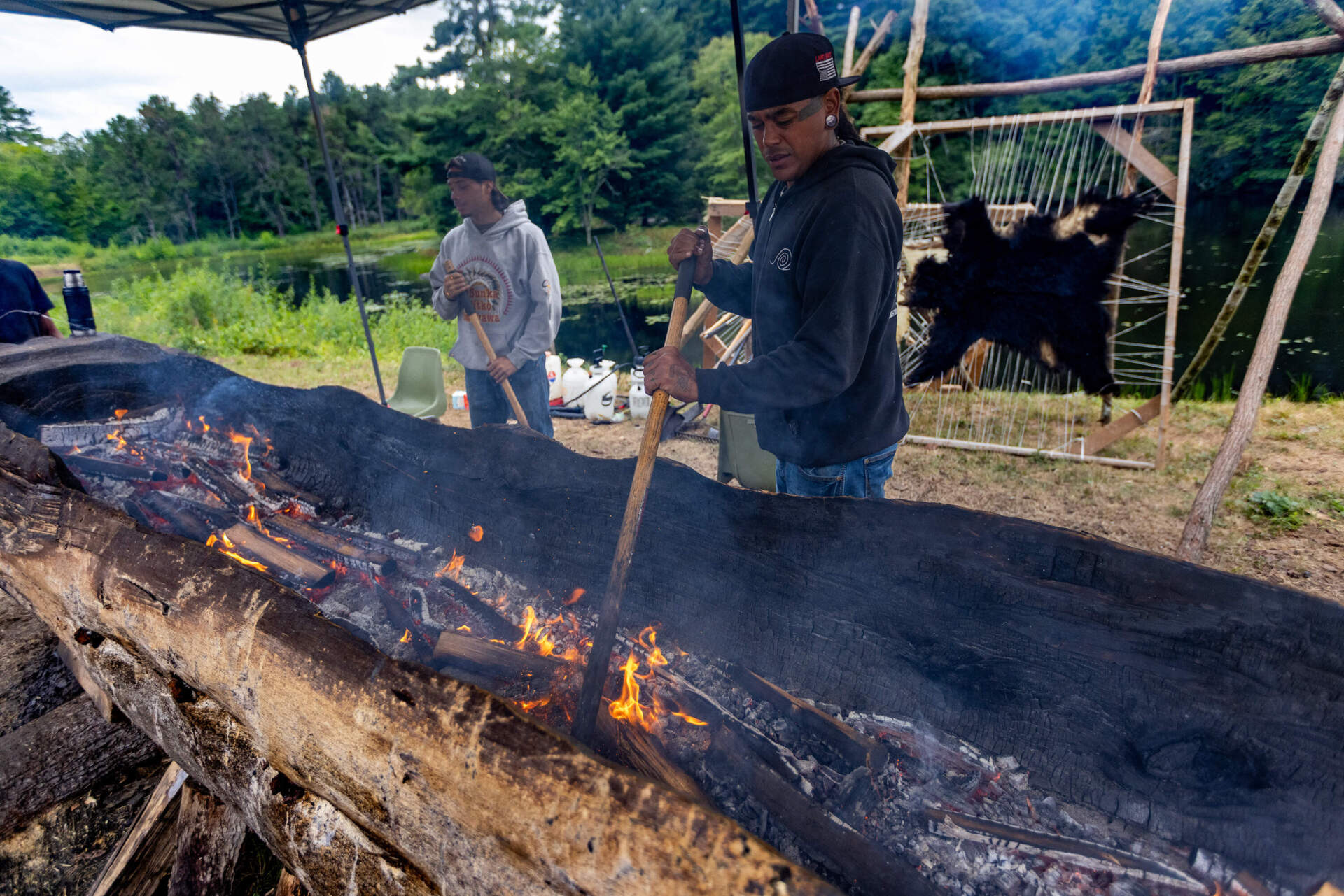 Andre StrongBearHeart Gaines-Roberson Jr. tends to the fire during a mishoon burning camp at the Norcross Wildlife Foundation in Wales, Massachusetts. (Jesse Costa/WBUR)