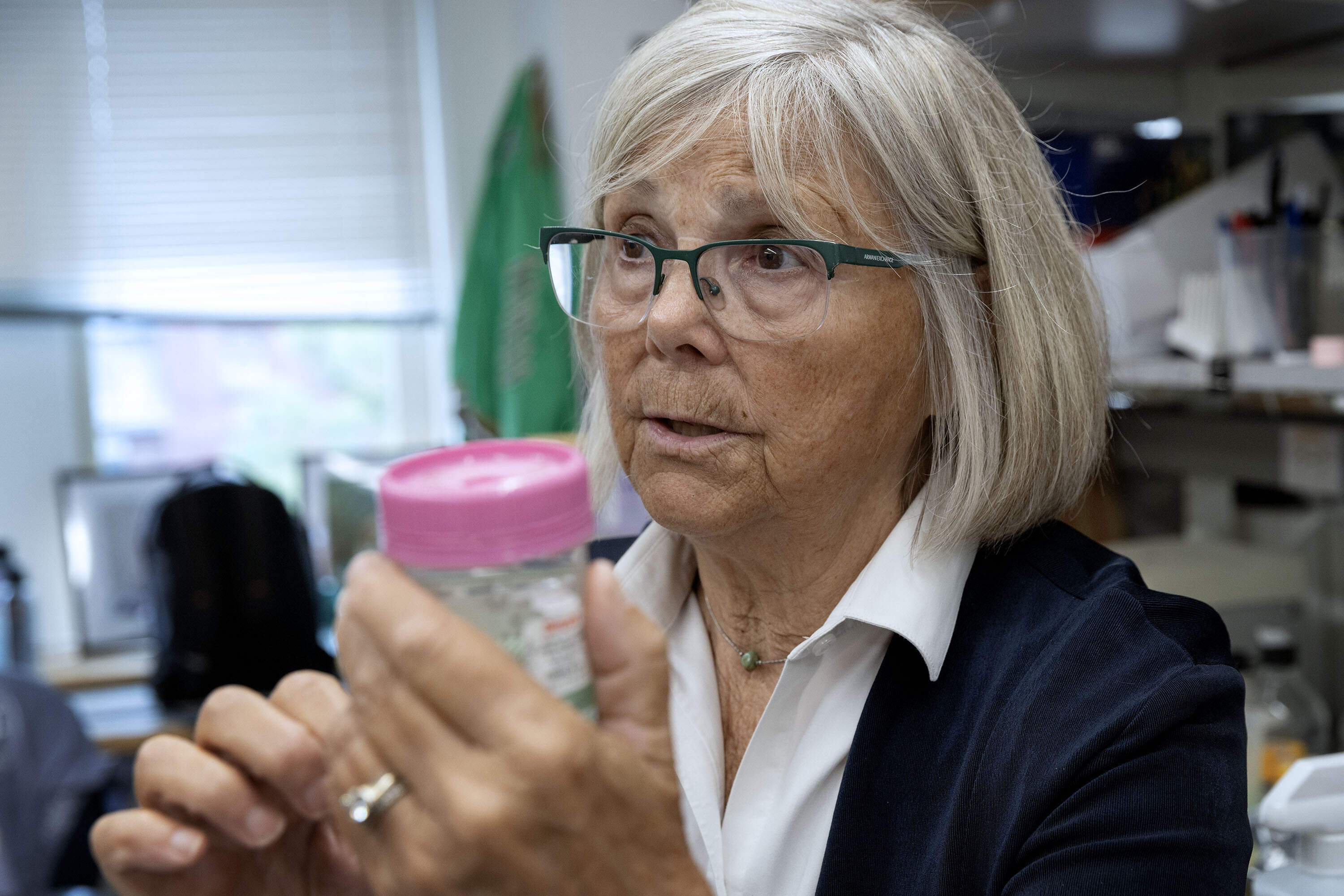 Joan Brugge holds a sample container inside Harvard Medical School's Brugge Lab. (Robin Lubbock/WBUR)