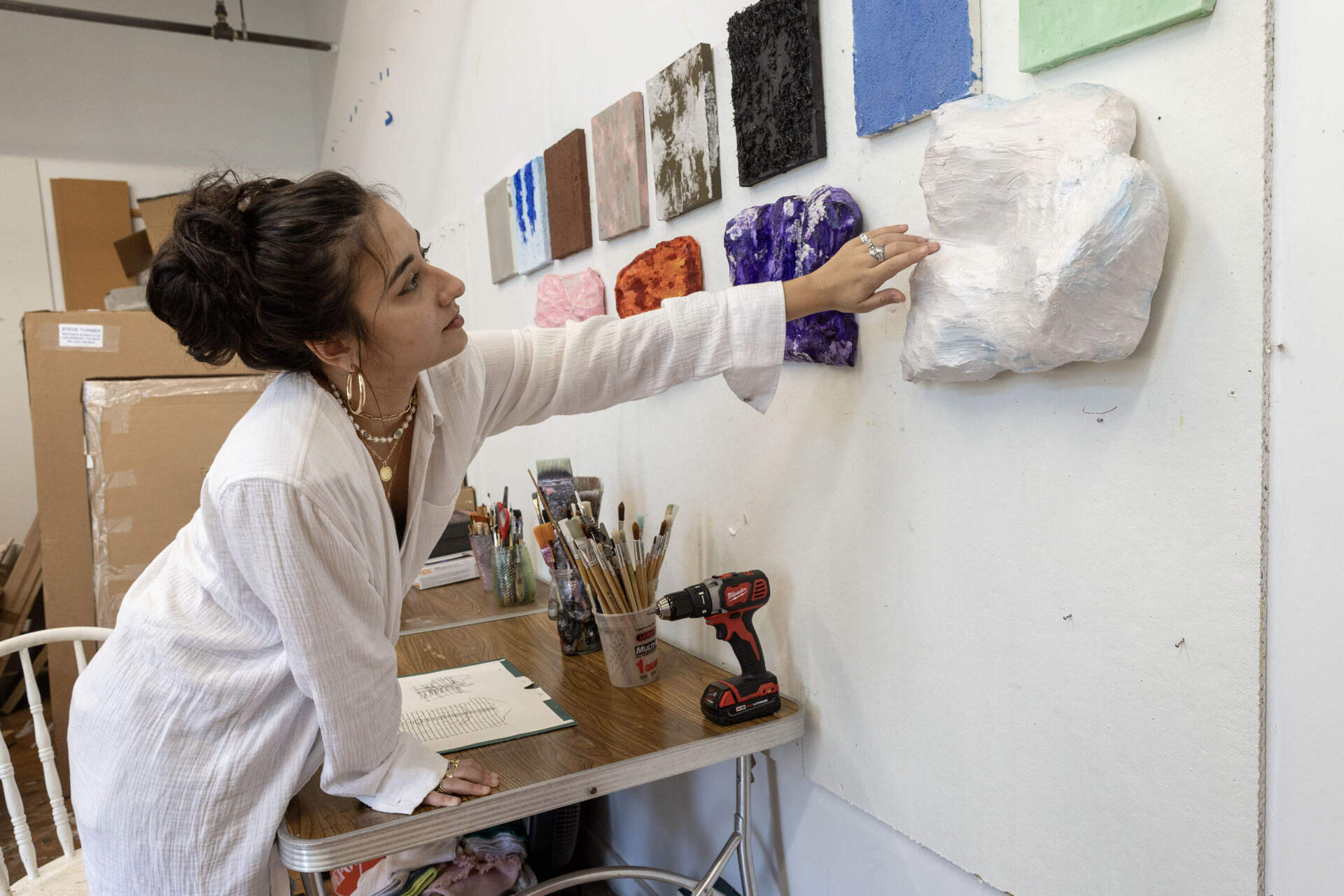 Nanajian reaches oUT TO FEEL THE TEXTURE OF ONE OF ONE WALLED SCUNTEDS. (Robin lubbock / wbur)