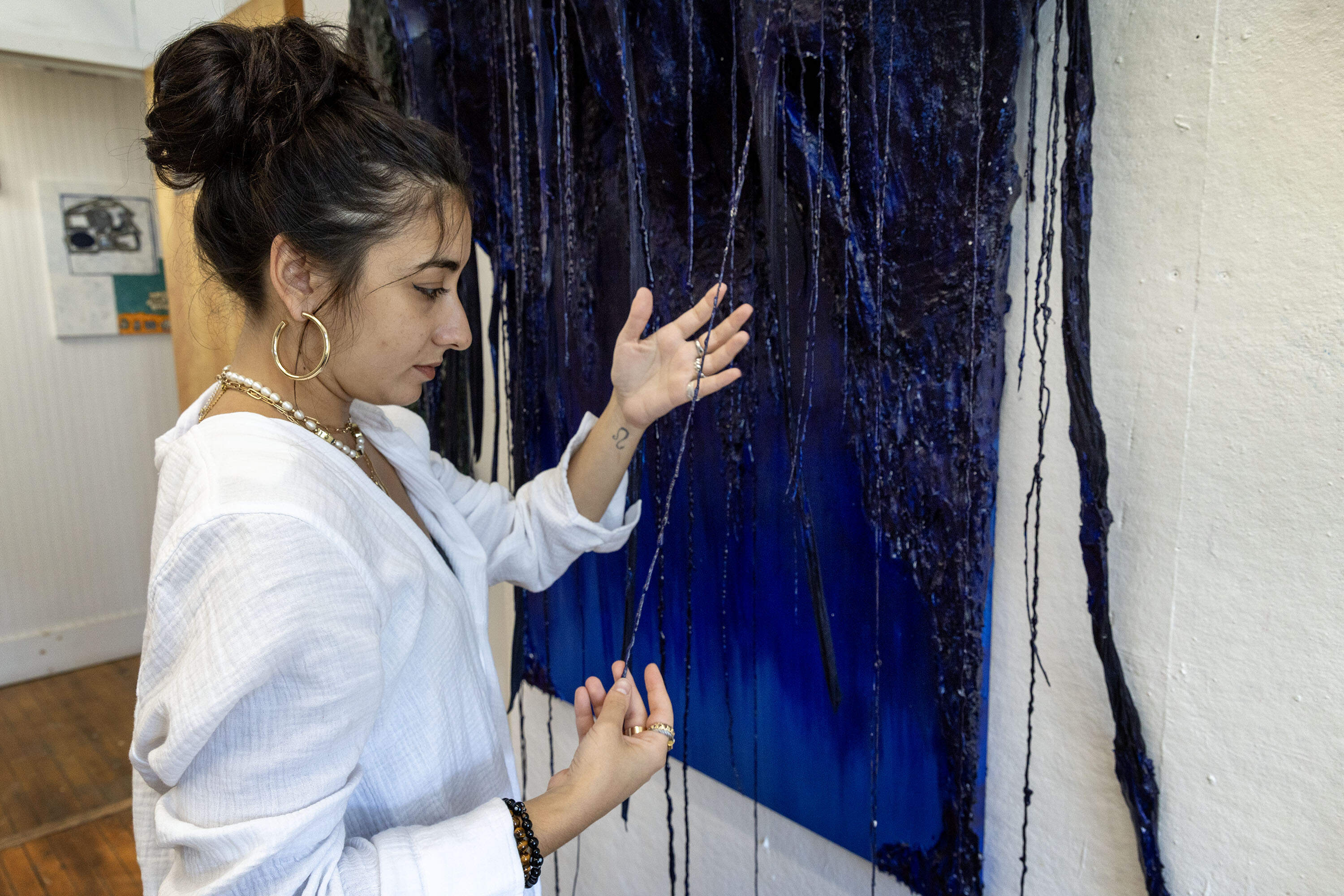 Nanajian examines one on the branches of her sculpture "Watery Willow" in her studio in Somerville. (Robin Lubbock/WBUR)