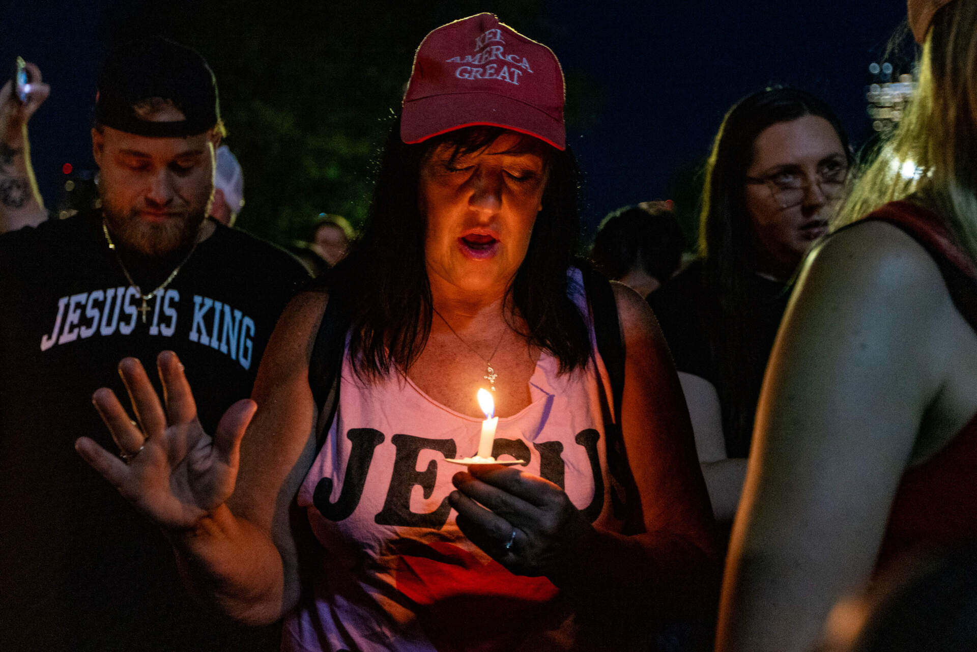 A woman joins the whole group as they pray and recite the Our Father during the vigil for Charlie Kirk. (Jesse Costa/WBUR)