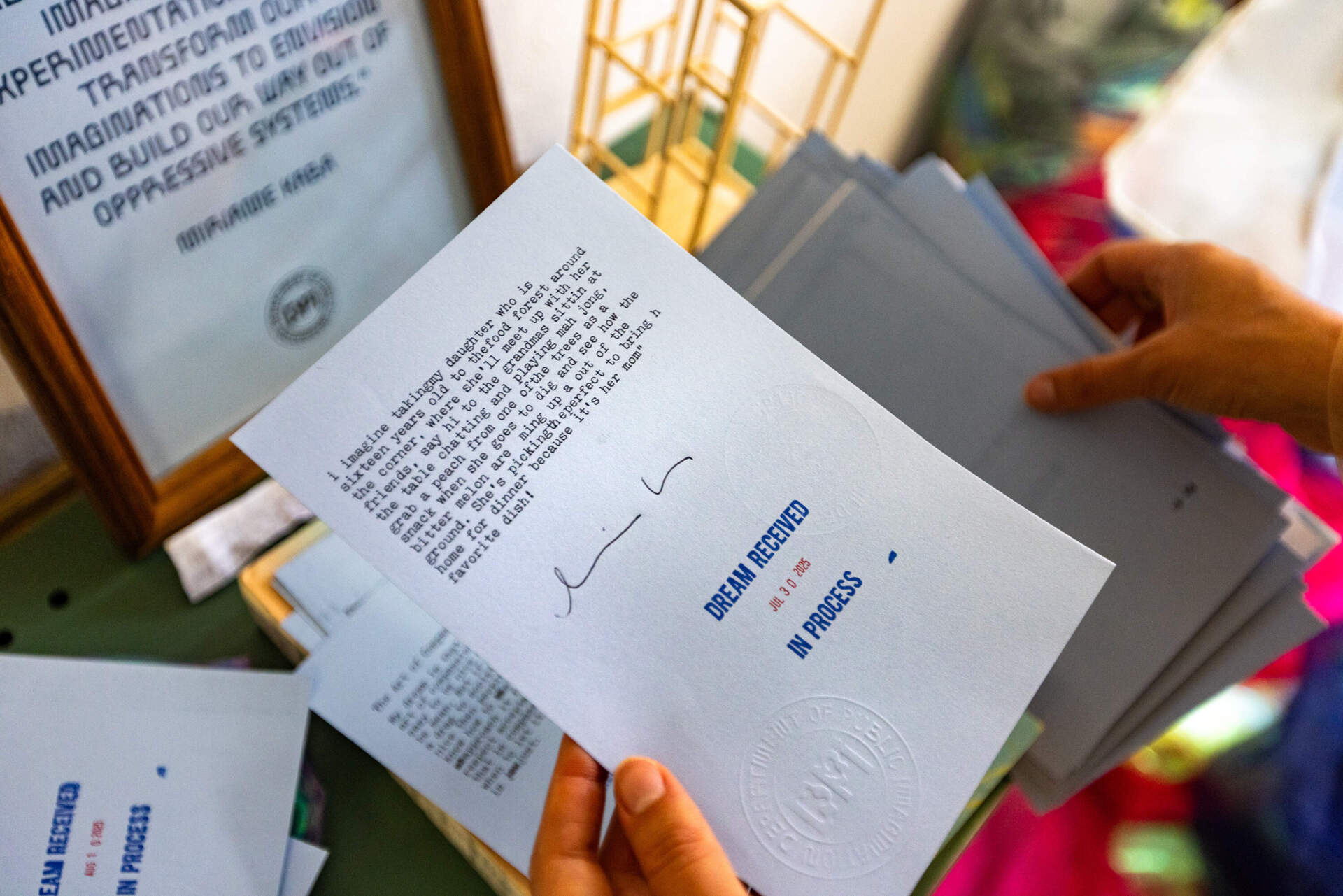 bi flips through a collection of typed dreams fulfilled during the Department of Public Imagination project, including this one from Boston Mayor Michelle Wu. (Jesse Costa/WBUR)