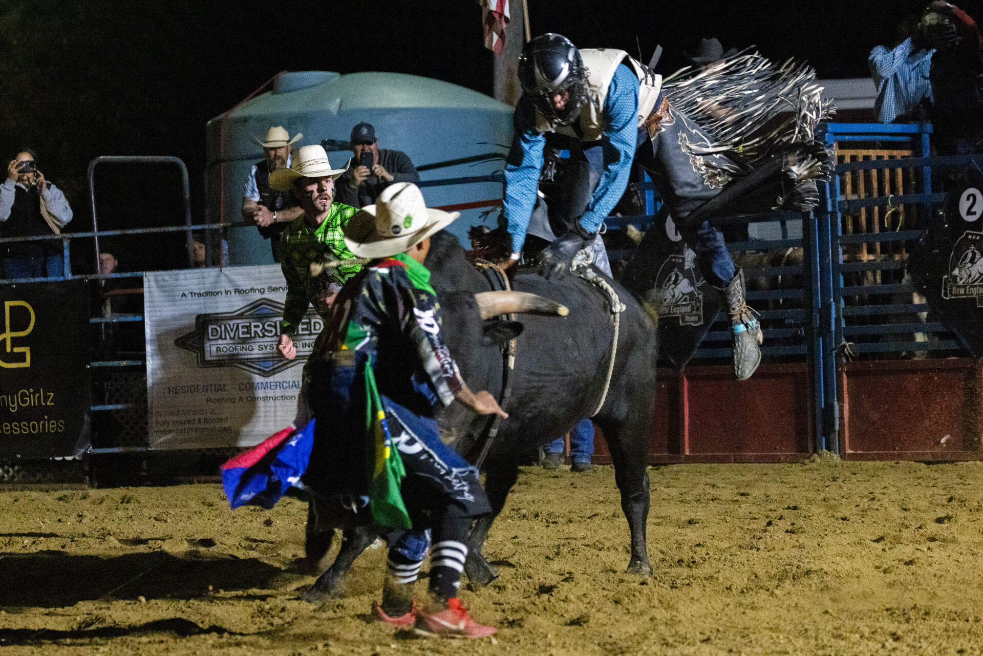 Gilson Duarte Pereira dismounts Whiskey Bent after riding for eight seconds during the professional division of the bull riding competition at the New England Rodeo at the Rochester Country Fairgrounds. (Jesse Costa/WBUR)