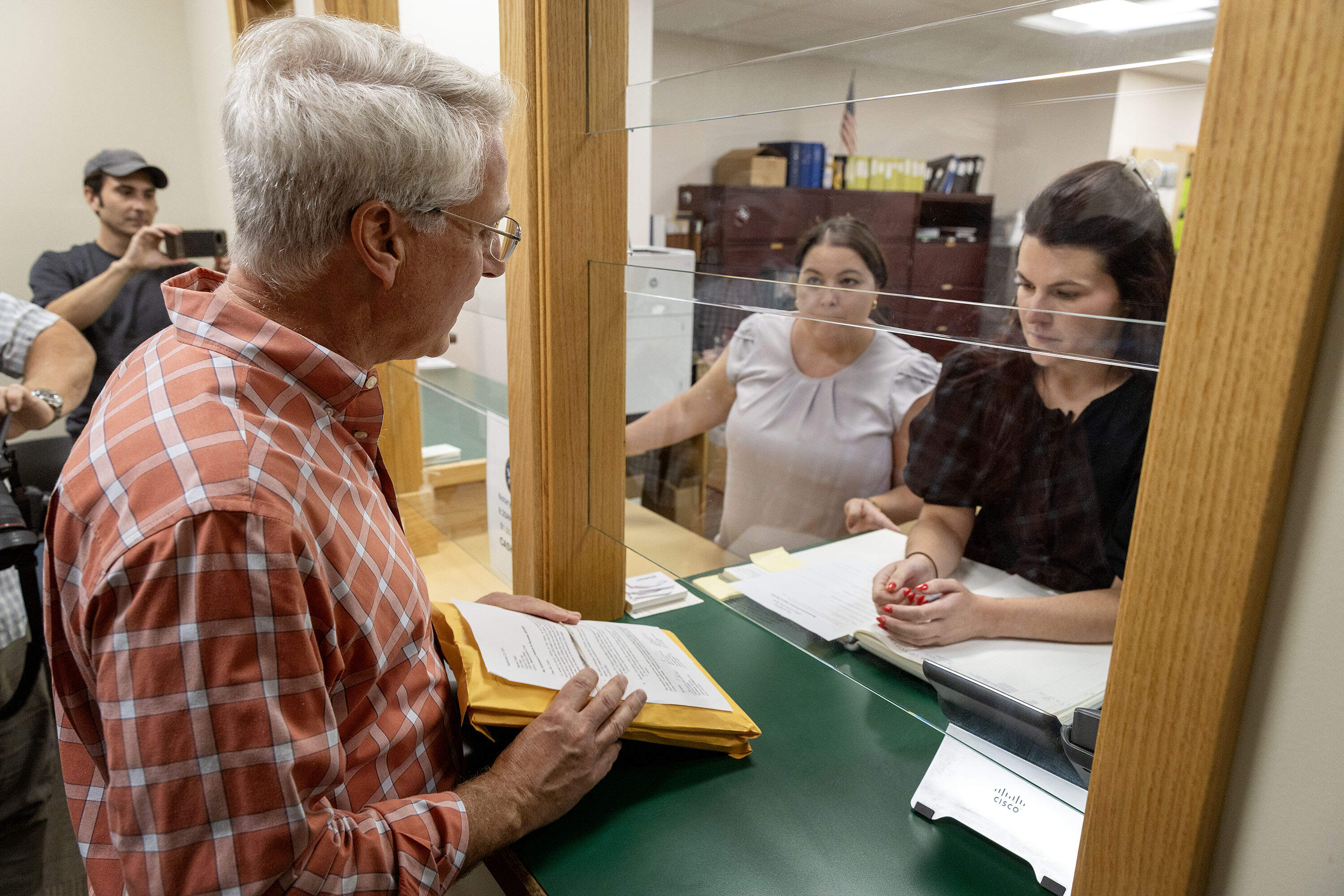 Steve Perdios, a leader of Quincy Citizens for Fair Raises, hands in an envelope of signature pages at the elections office at Quincy City Hall. (Robin Lubbock/WBUR)
