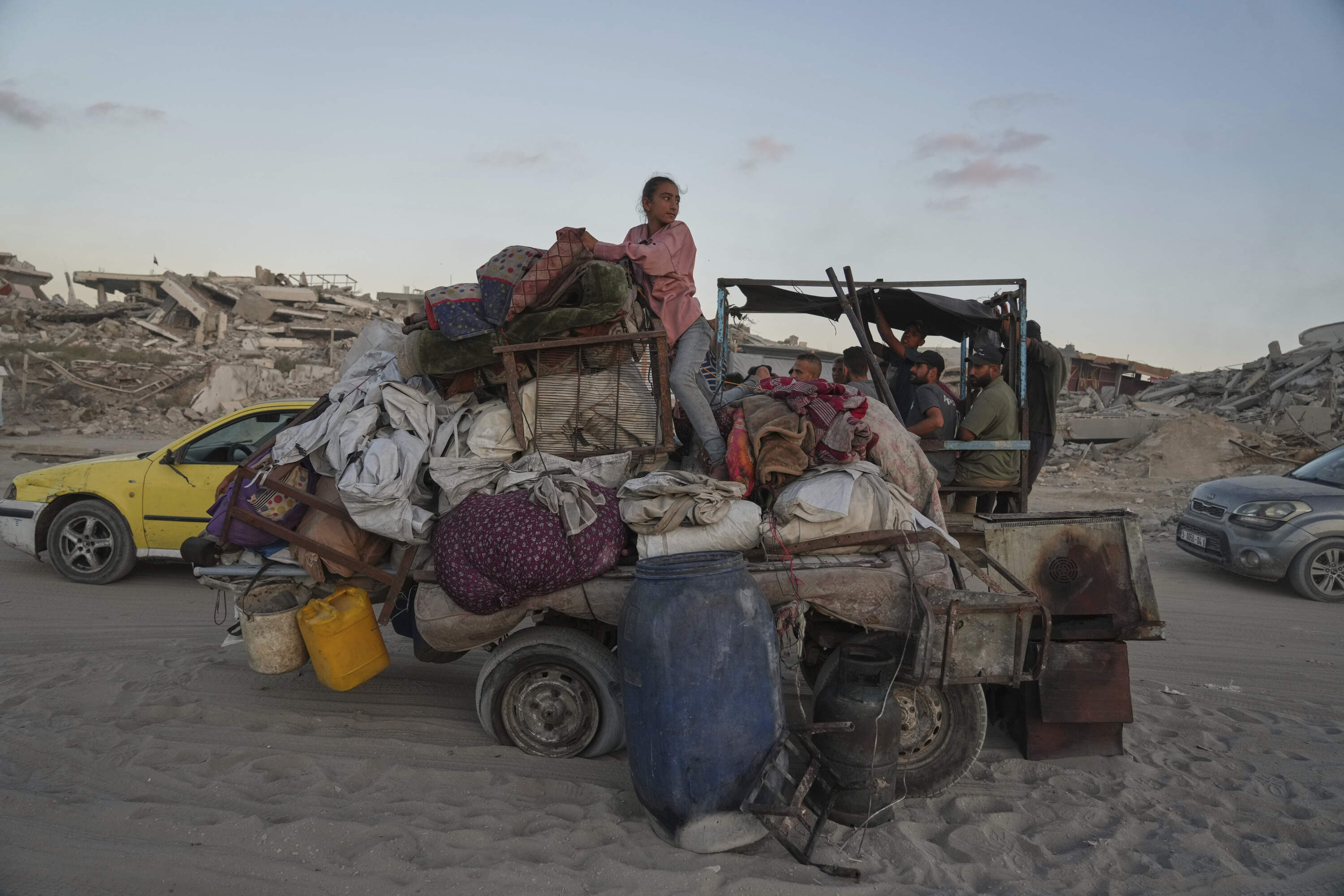 A displaced Palestinian youth stands on top of a broken cart as she flees northern Gaza Strip with her family, moving with their belongings along the Sea Road, in Gaza City, Monday, Sept. 1, 2025. (Jehad Alshrafi/AP)
