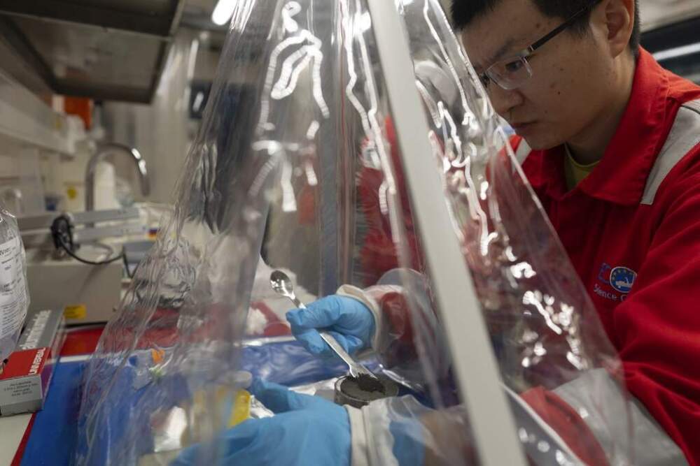 Expedition 501 researcher Xinxu Zhang, of Shenzhen University China, works in a container to ensure a sterile environment aboard the Liftboat Robert platform. (Carolyn Kaster/AP)
