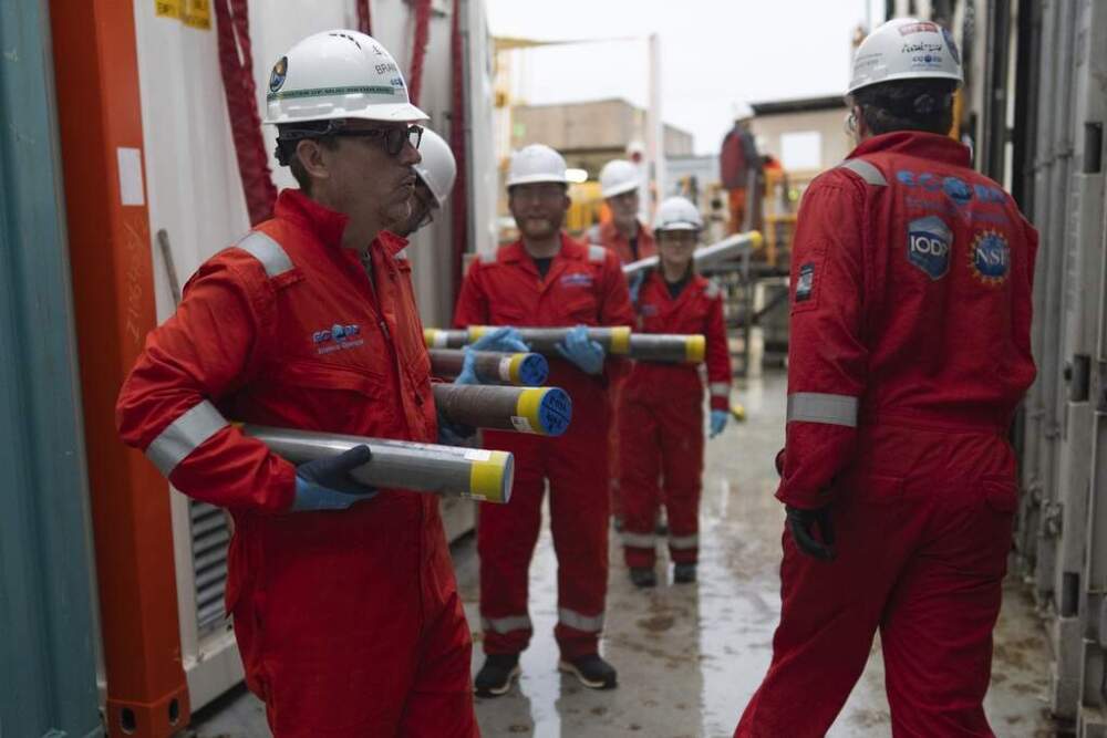 Researchers, including Expedition 501 co-chief scientist Brandon Dugan, carry cores to a cold storage container aboard the Liftboat Robert platform. (Carolyn Kaster/AP)